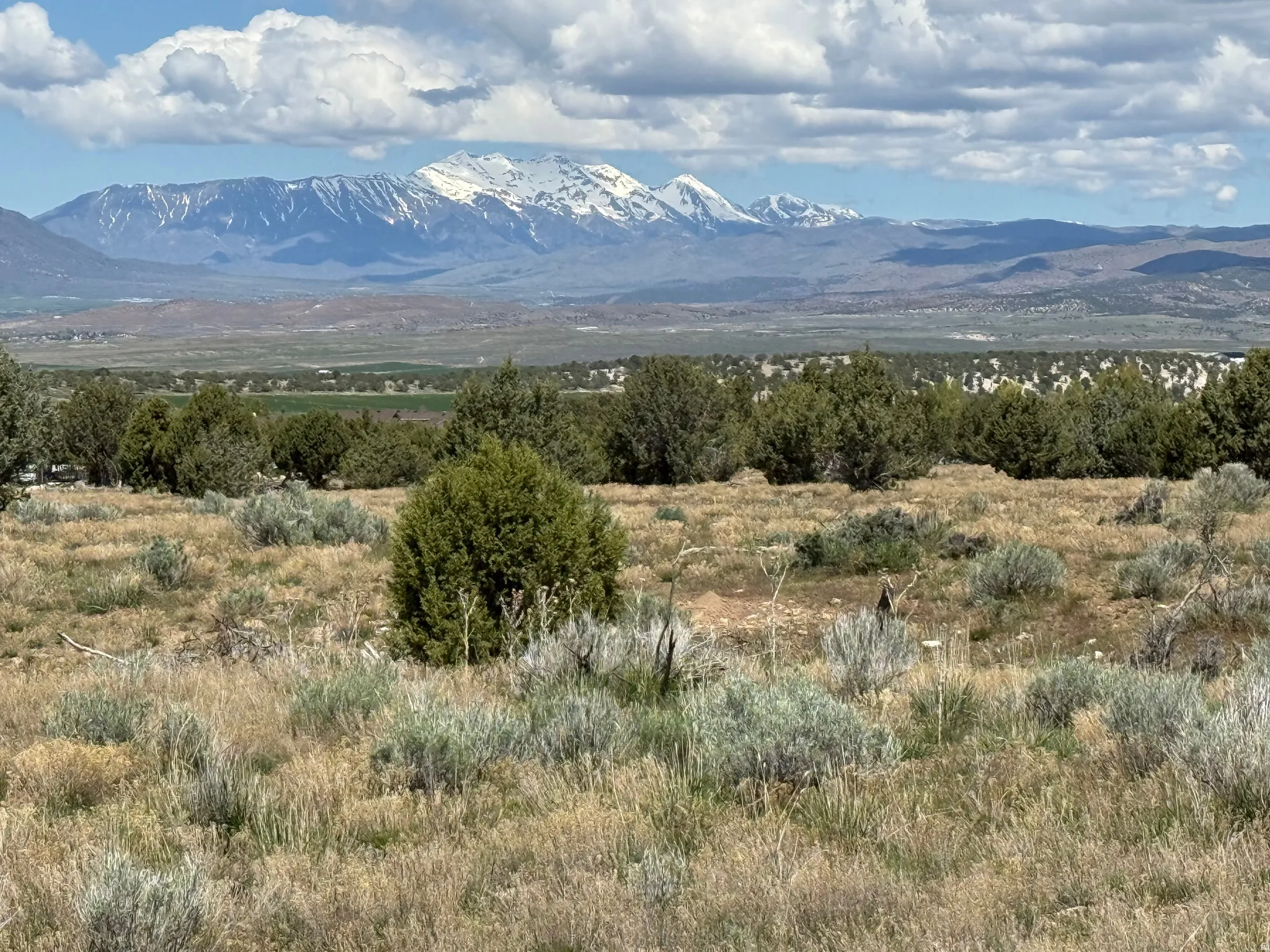 Expansive mountain landscape featuring snow-capped peaks under a partly cloudy sky