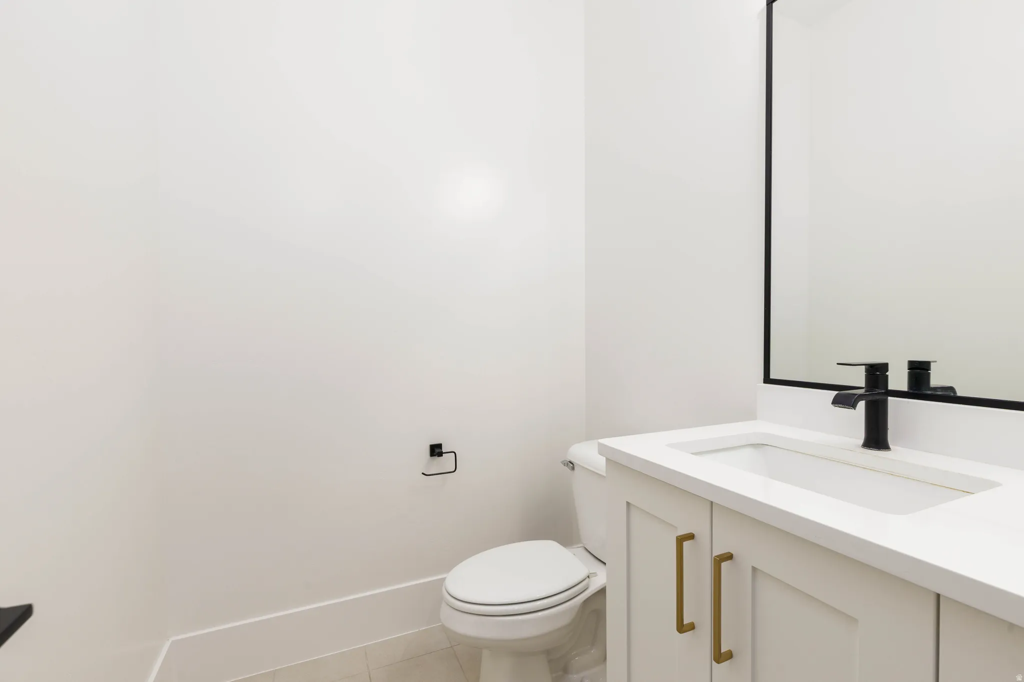 White vanity with a rectangular integrated sink, matte black faucet, and brass-tone hardware
