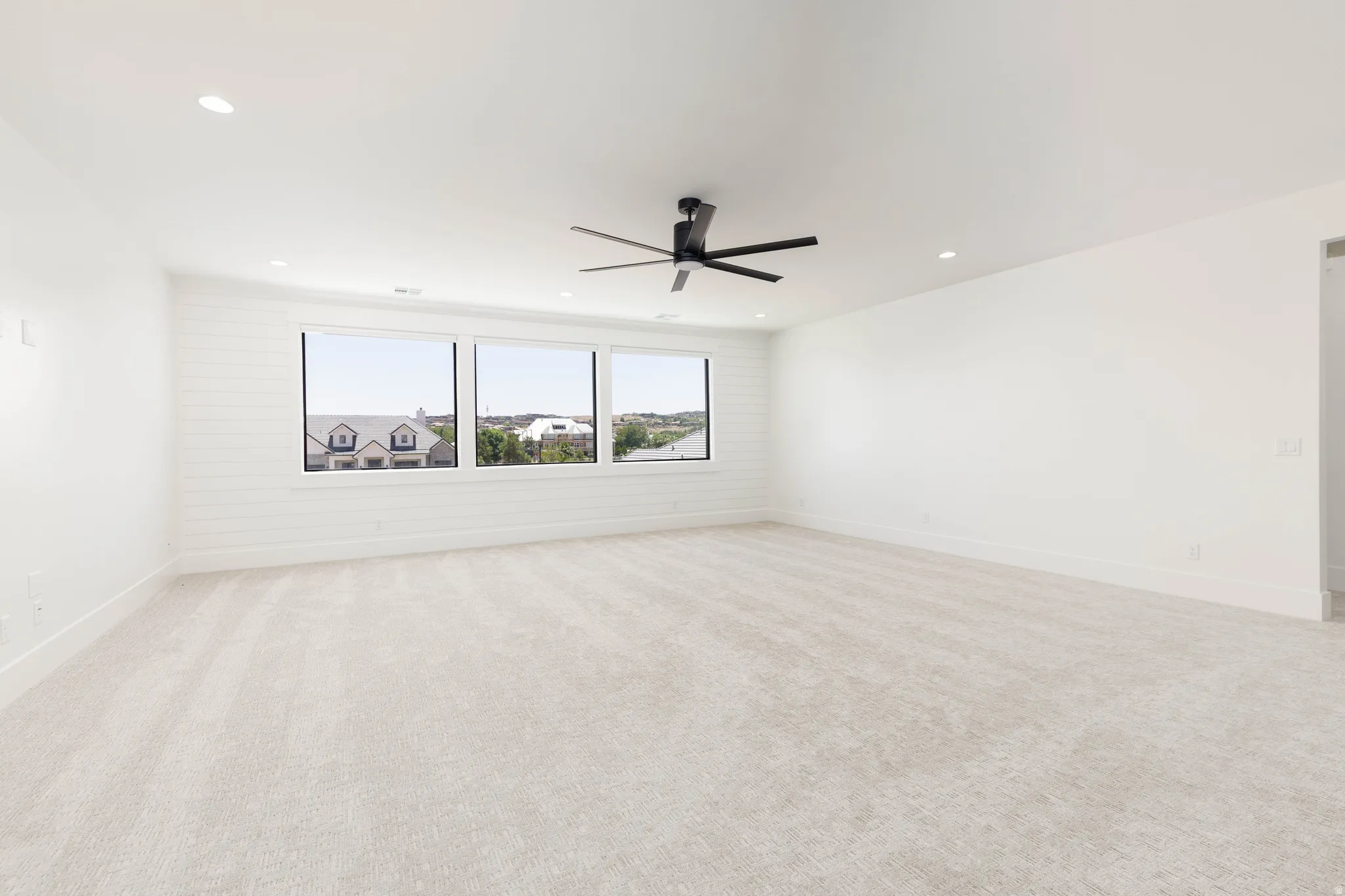 Spacious room featuring light-toned carpet flooring and recessed ceiling lighting
