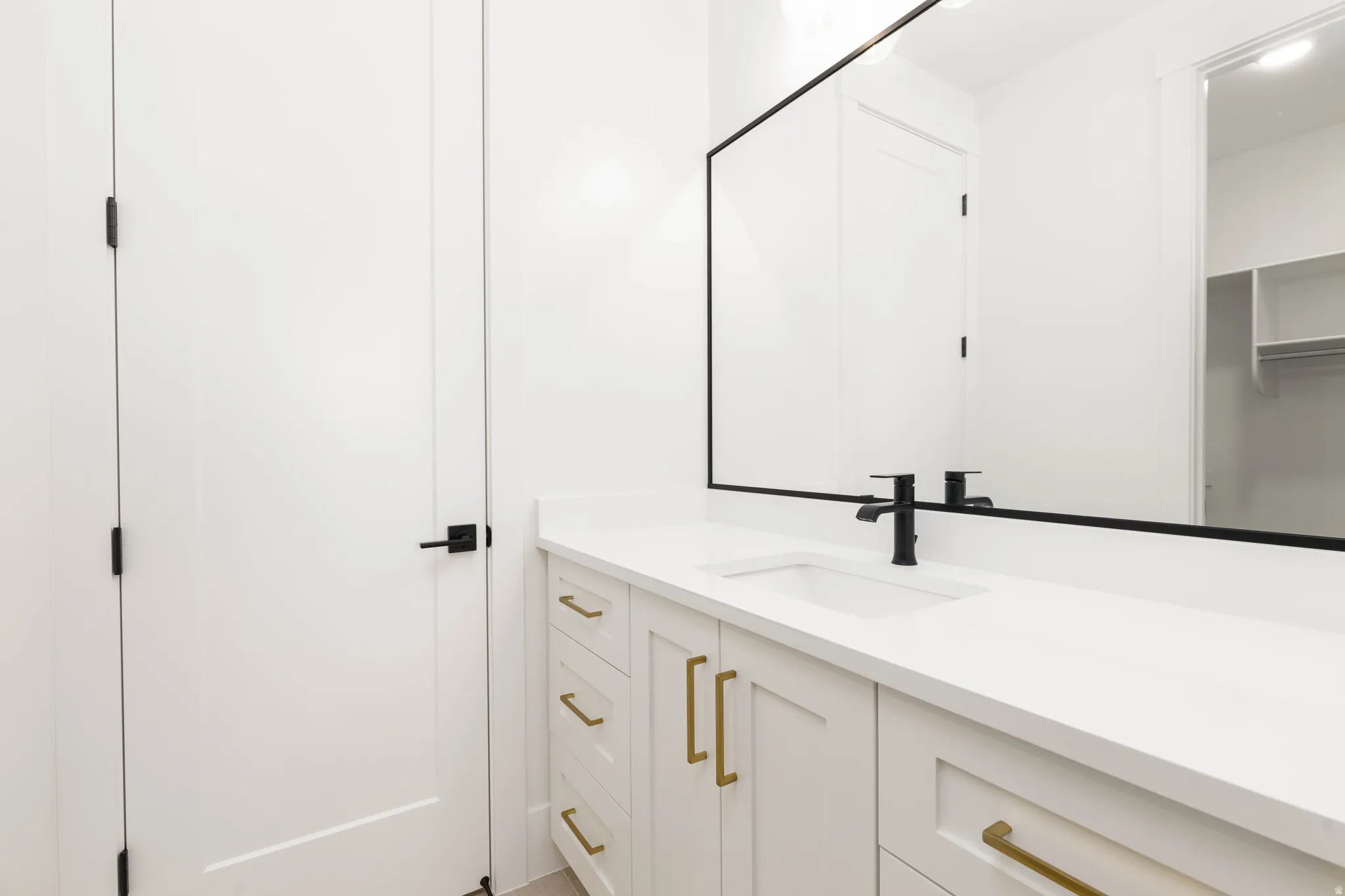 White vanity with gold-tone hardware, a white countertop, and an integrated rectangular sink