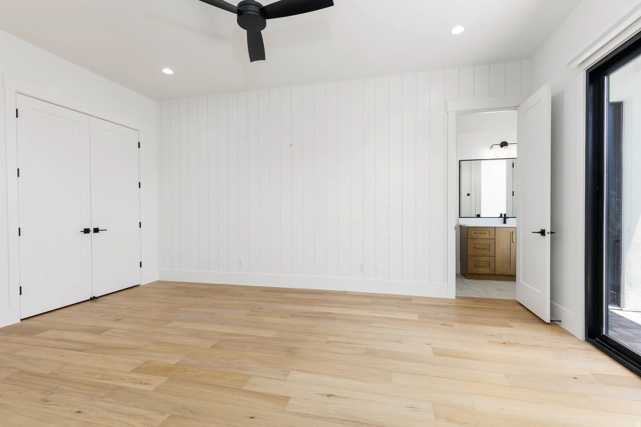 Spacious interior featuring wide plank wood-finish flooring, a white shiplap accent wall, and recessed lighting