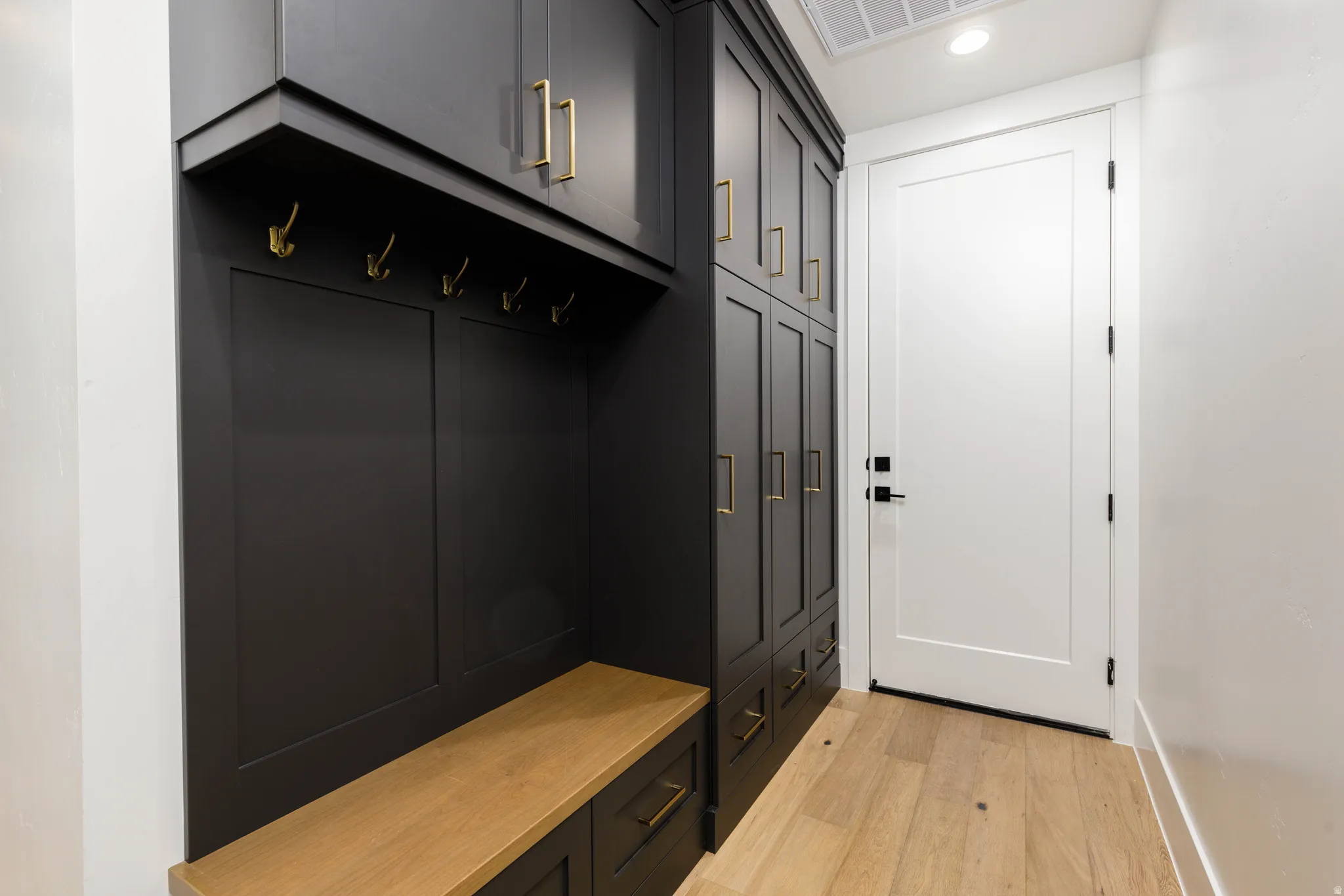 Custom built-in entryway storage with rich dark cabinetry and gold-toned hardware