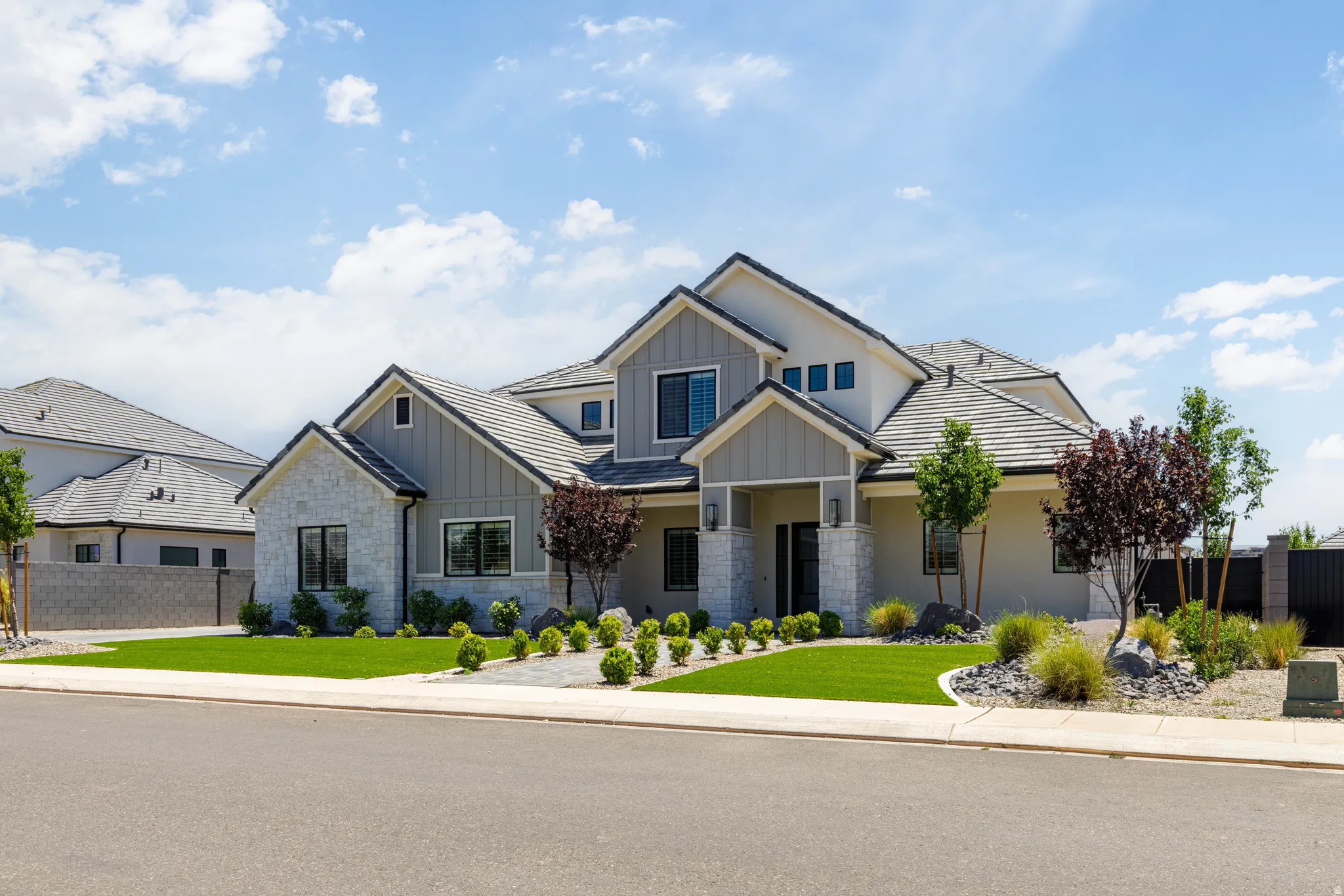 Contemporary residence featuring multi-textured facade, a covered entry, and a symmetrical roofline with dark tile