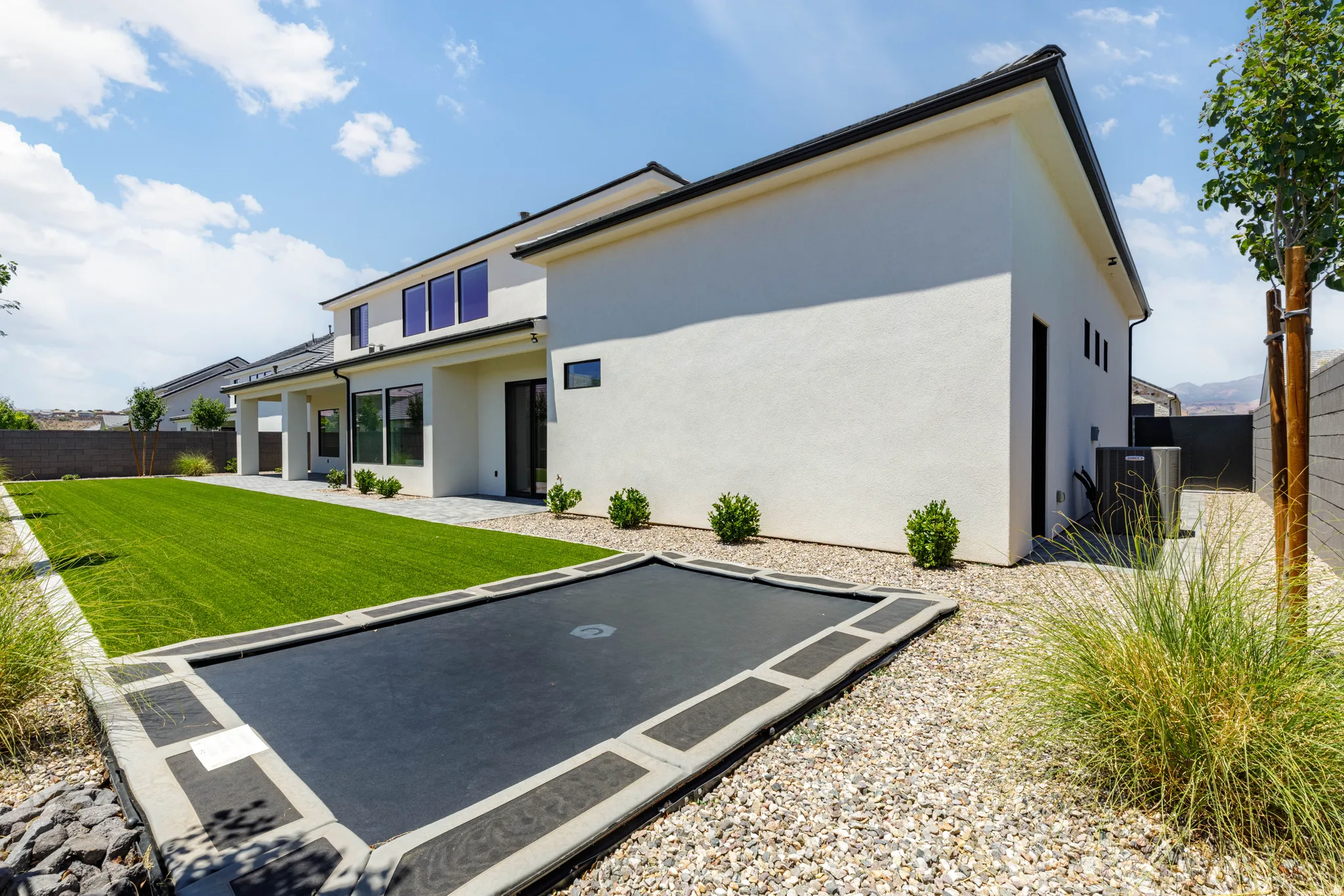 Rear exterior of a contemporary home featuring a stucco finish and dark trim