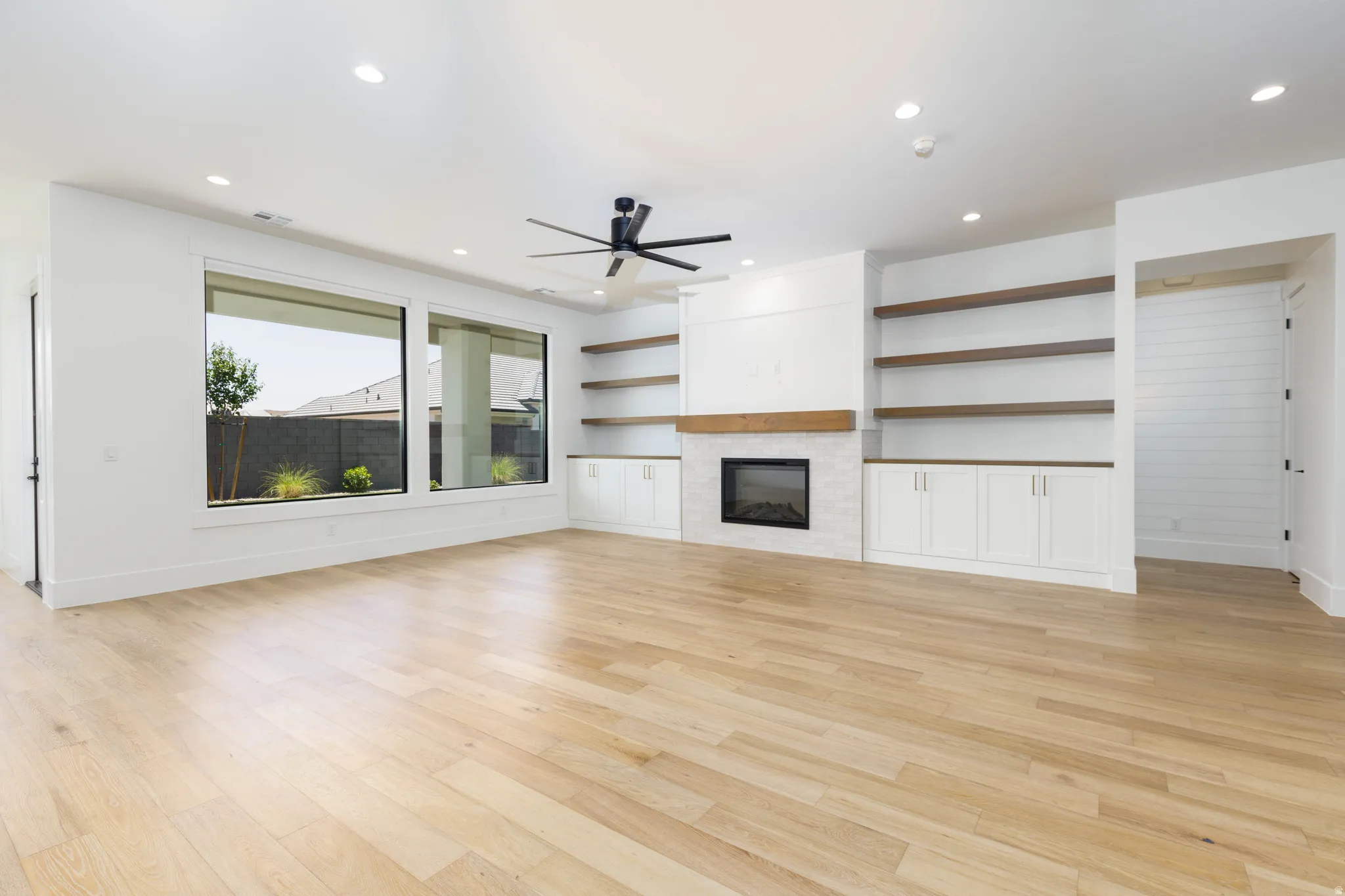 Spacious room featuring wood-finish flooring, a contemporary ceiling fan, and recessed lighting