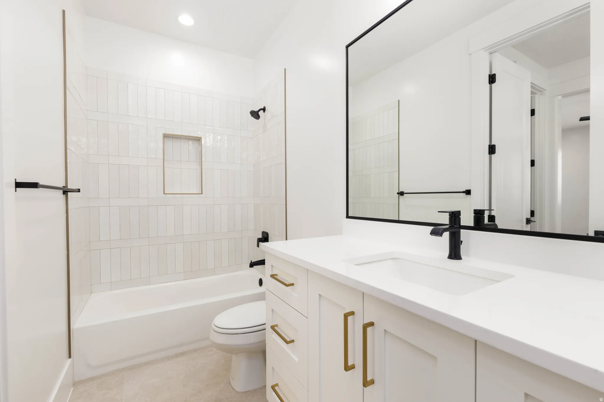 White bath vanity with integrated sink and matte black faucet, featuring a large framed mirror