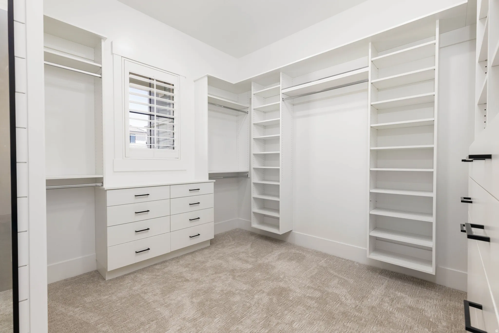 Custom closet system featuring extensive shelving, hanging rods, and built-in drawers with matte black hardware