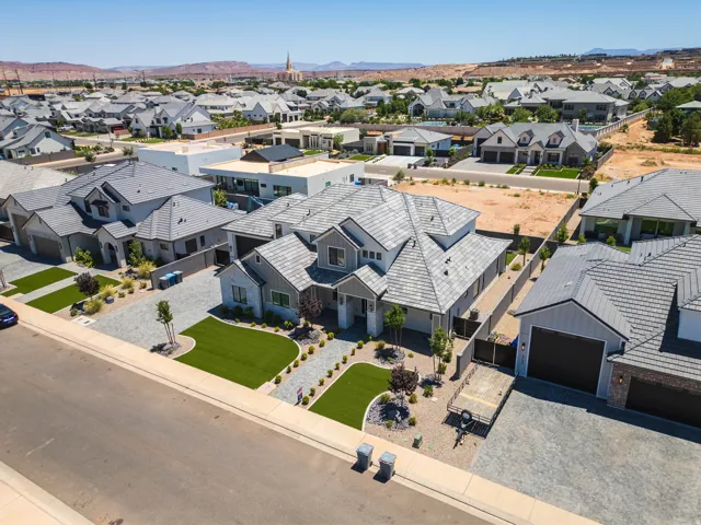 Contemporary architecture featuring an expansive paver driveway, artificial turf landscaping, and a multi-gabled roofline