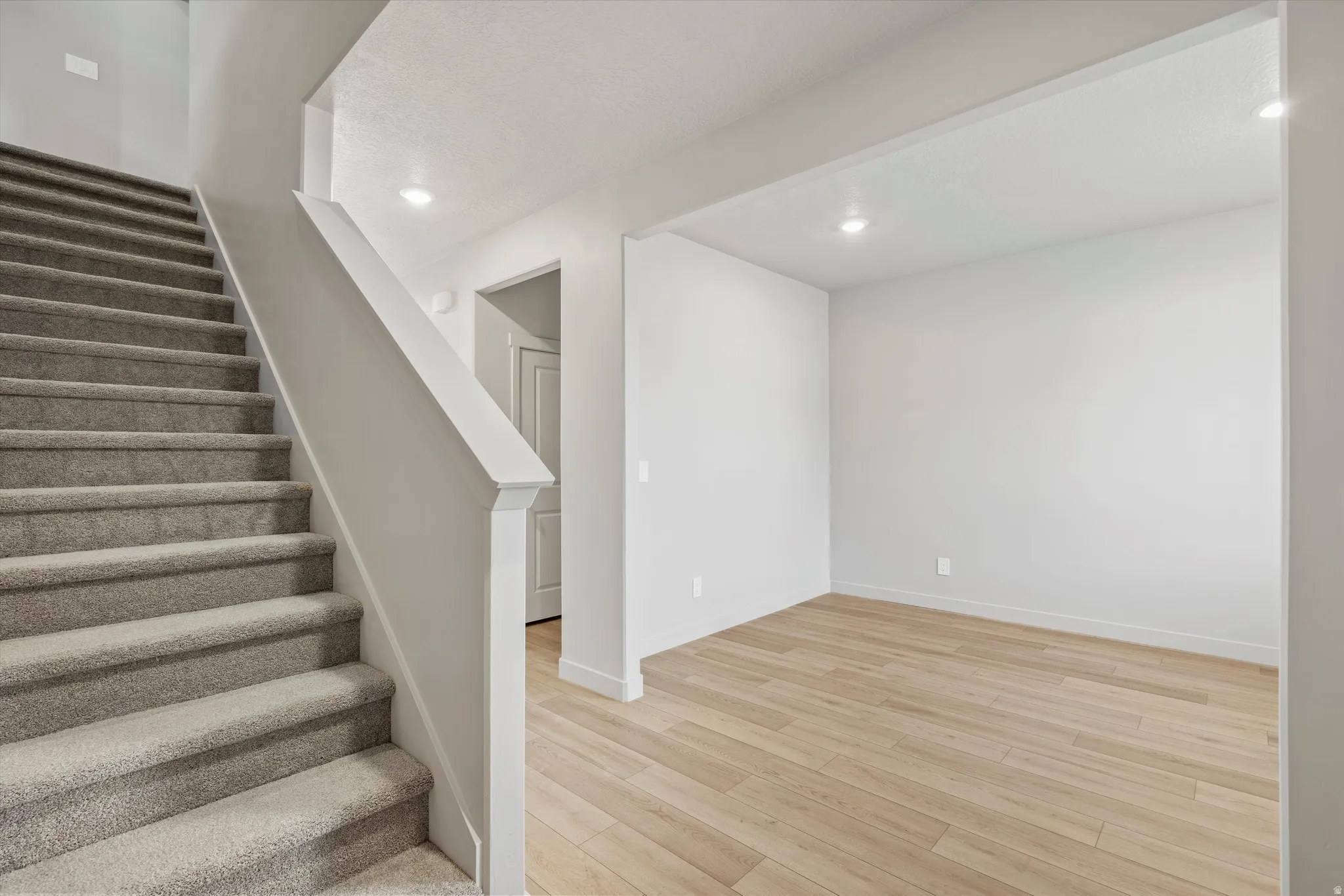 Open room with wood-finish flooring, recessed lighting, and white baseboards