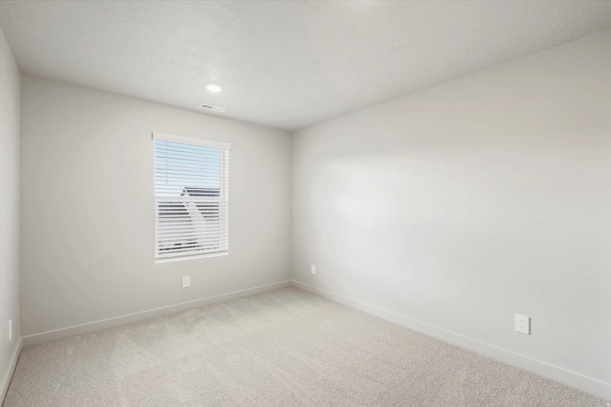 Neutral tone interior room featuring a window with white blinds
