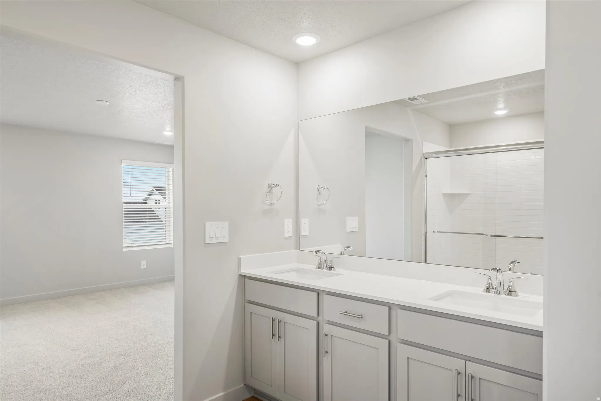 Bathroom featuring a dual vanity with light gray cabinetry, white countertops, and undermount sinks