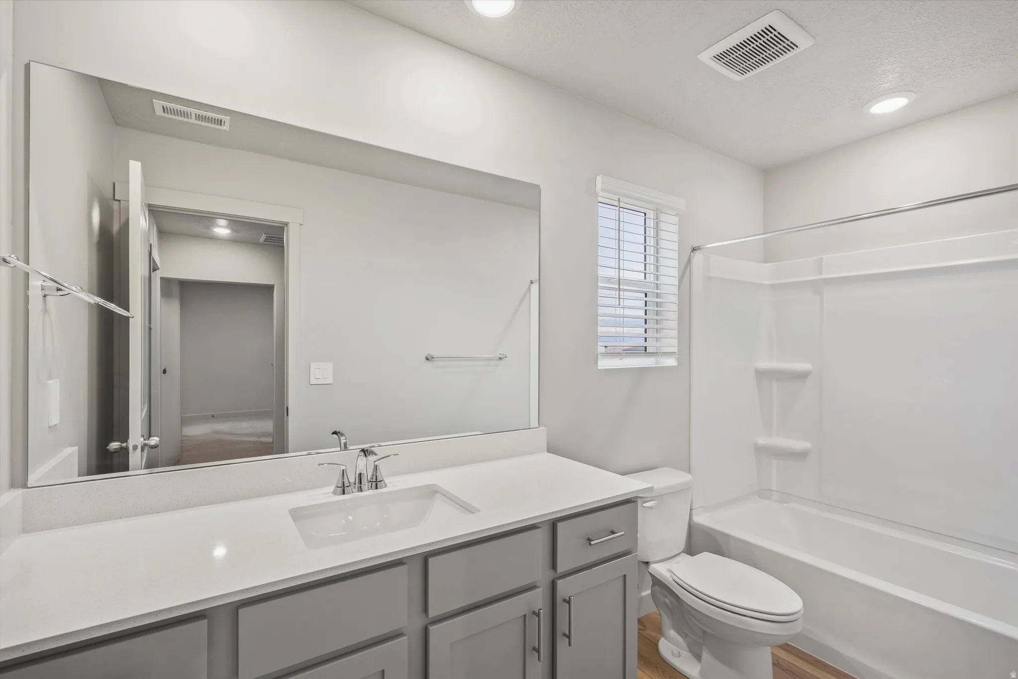 Bathroom featuring a vanity with an integrated sink, polished chrome faucet, and gray cabinetry