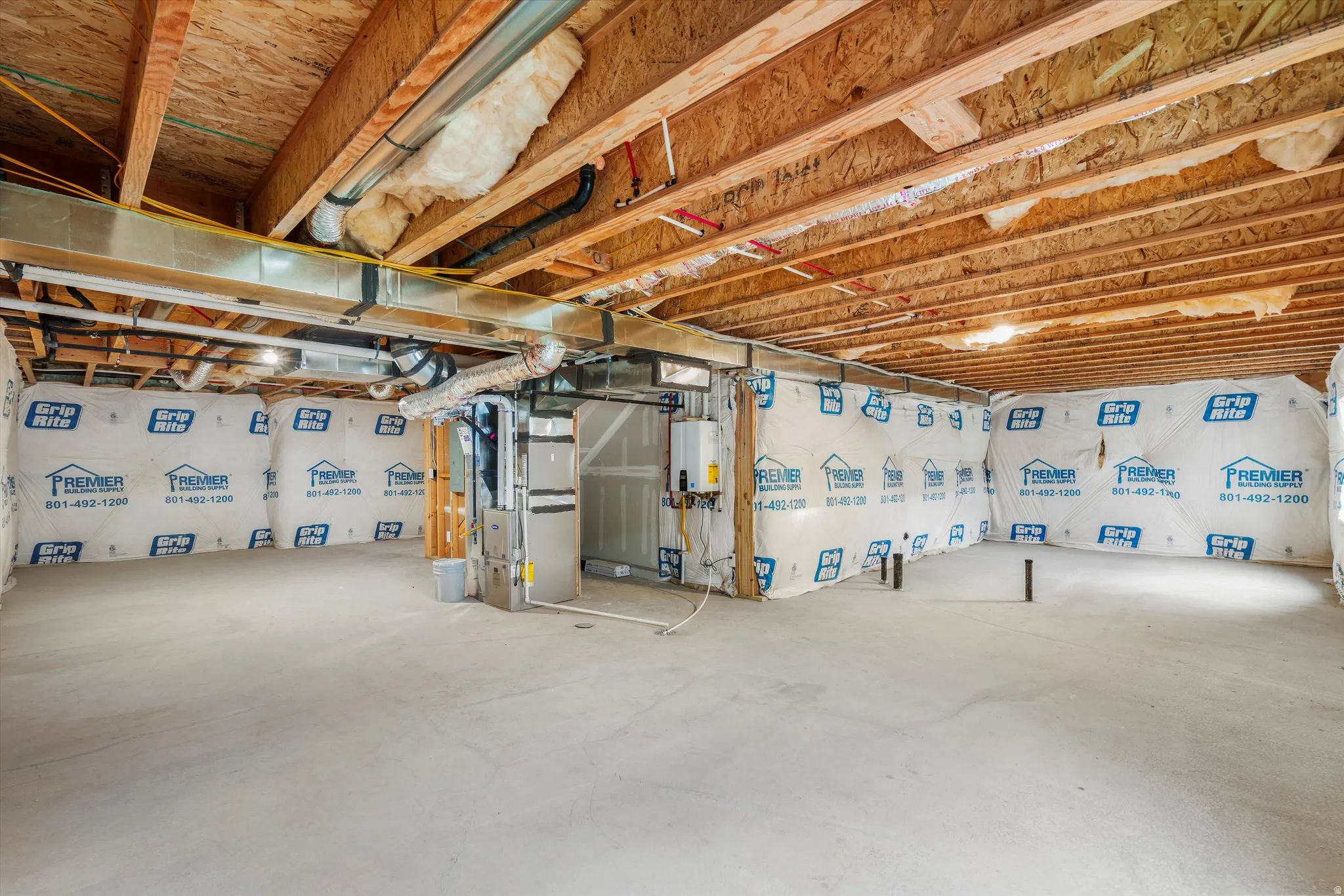 Unfinished basement space featuring a concrete floor, exposed wood ceiling joists, and insulated perimeter walls