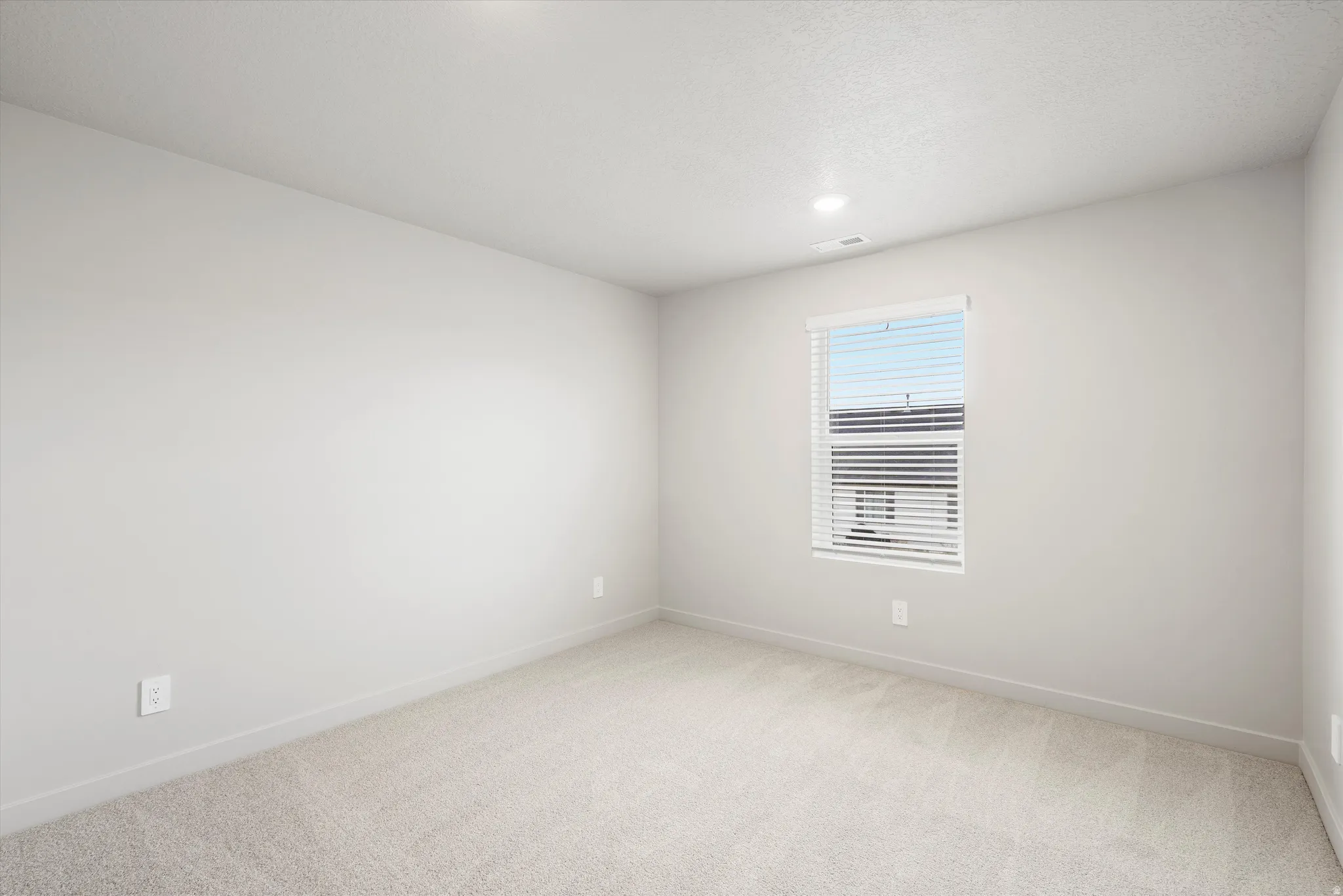 Room featuring light gray walls, neutral carpeting, a single window with white blinds, recessed lighting, and white baseboards