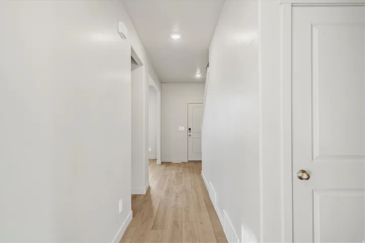 Hallway with wood-finish flooring, recessed lighting, and a neutral color palette