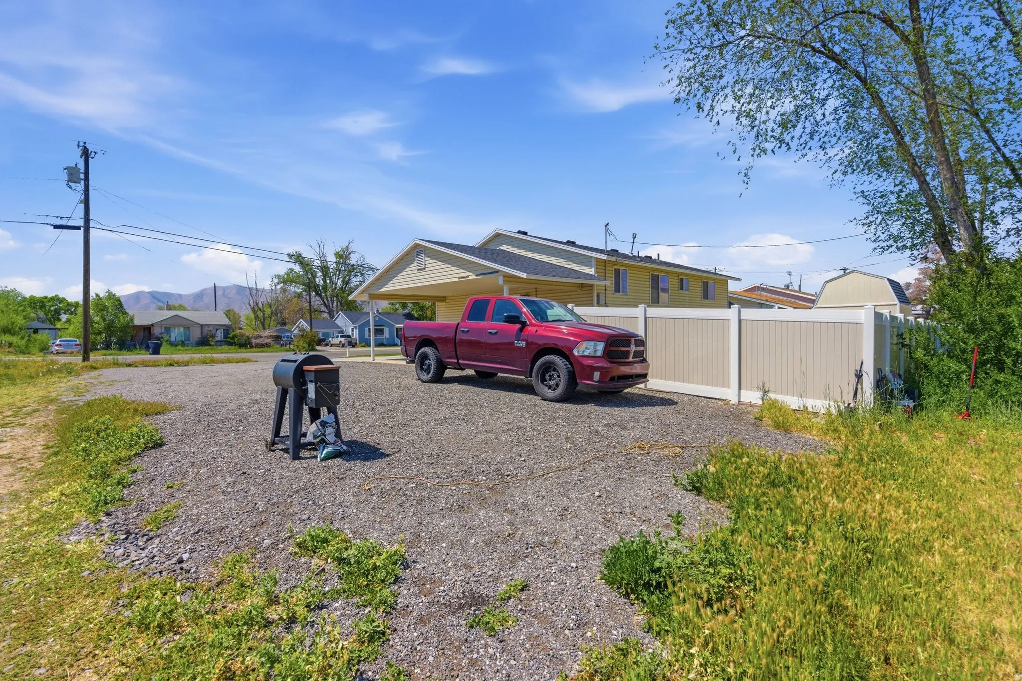 Gravel parking area featuring a detached carport structure