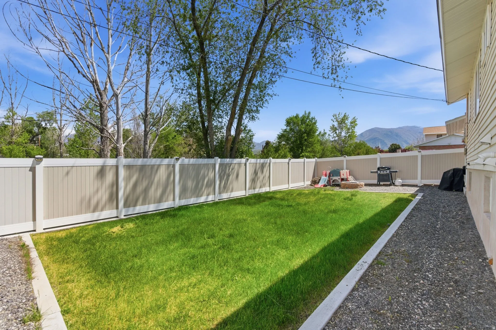 Expansive backyard featuring a manicured lawn, a gravel pathway, and a privacy fence