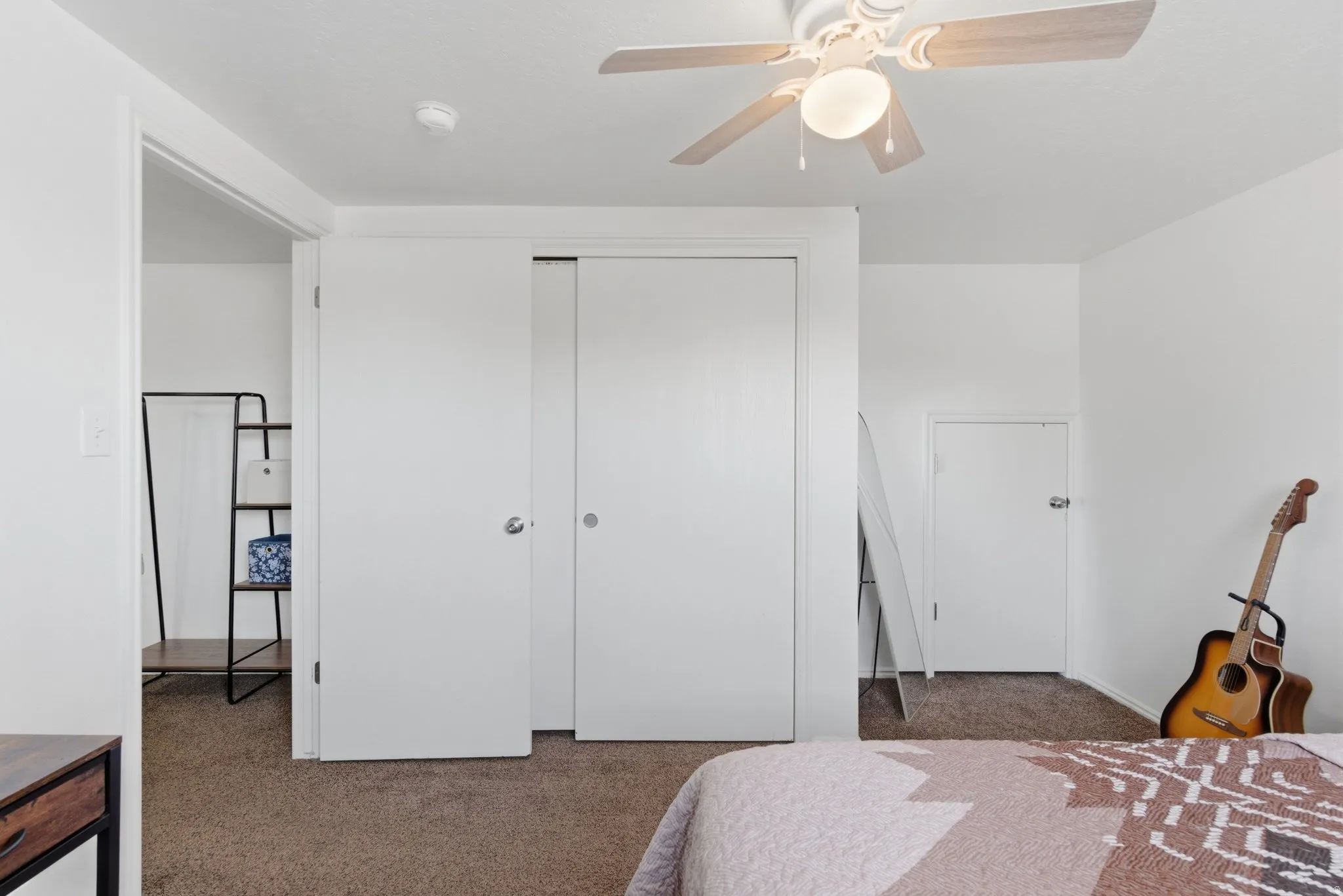 Carpeted room featuring white walls, a ceiling fan with light fixture, and white sliding closet doors