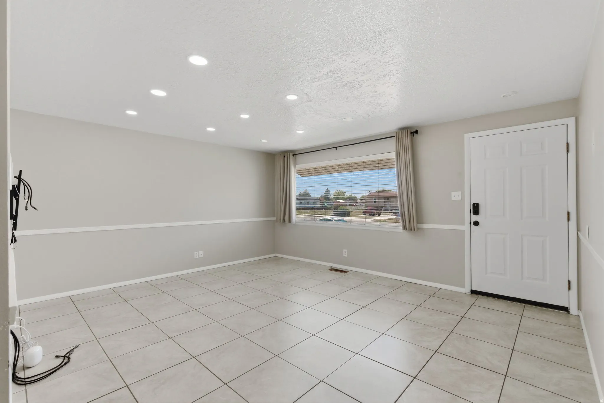 Living area featuring light gray walls with a decorative chair rail, recessed ceiling lighting, and a white paneled entry door