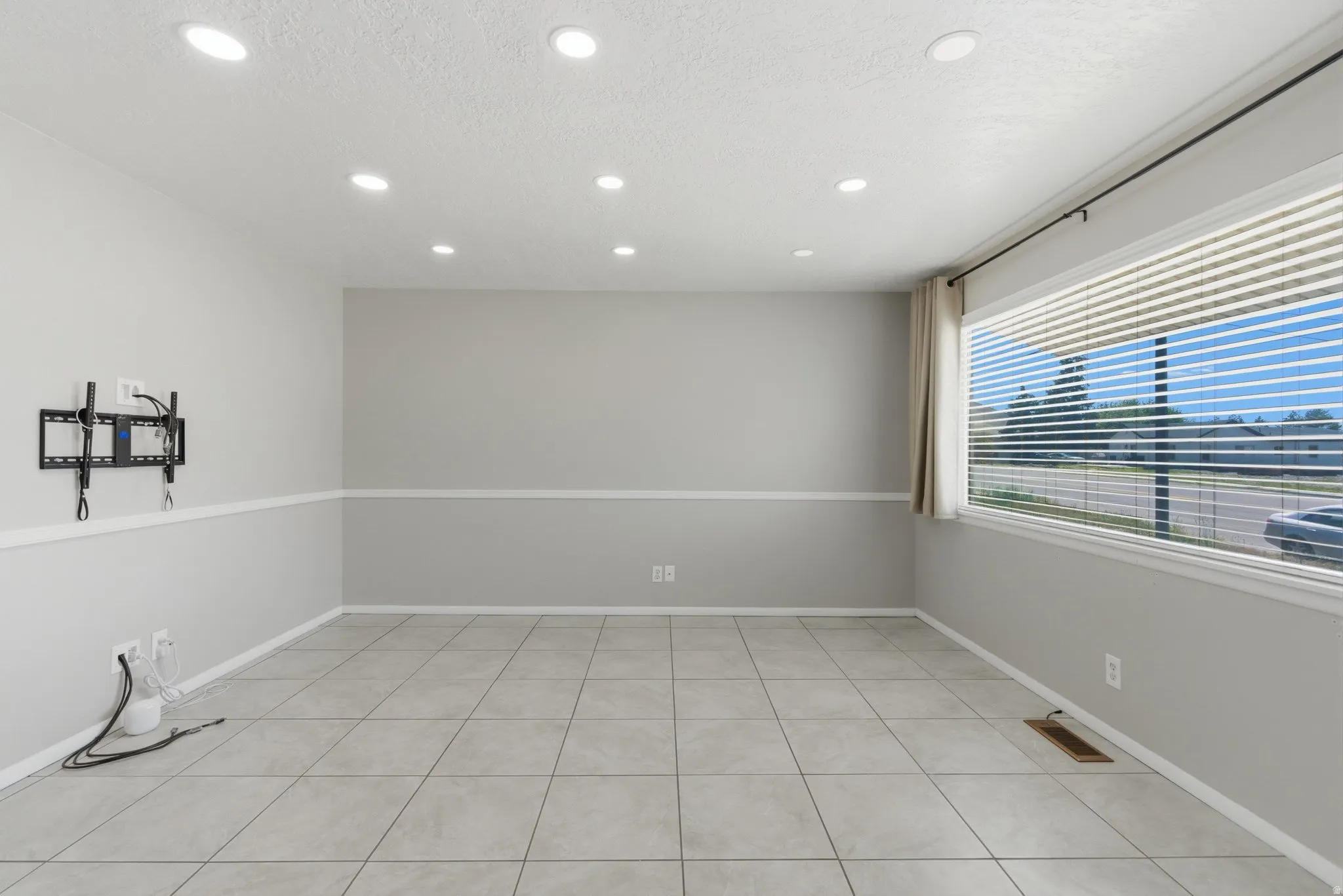 Spacious living area featuring light gray walls, a chair rail molding, and large format tile flooring