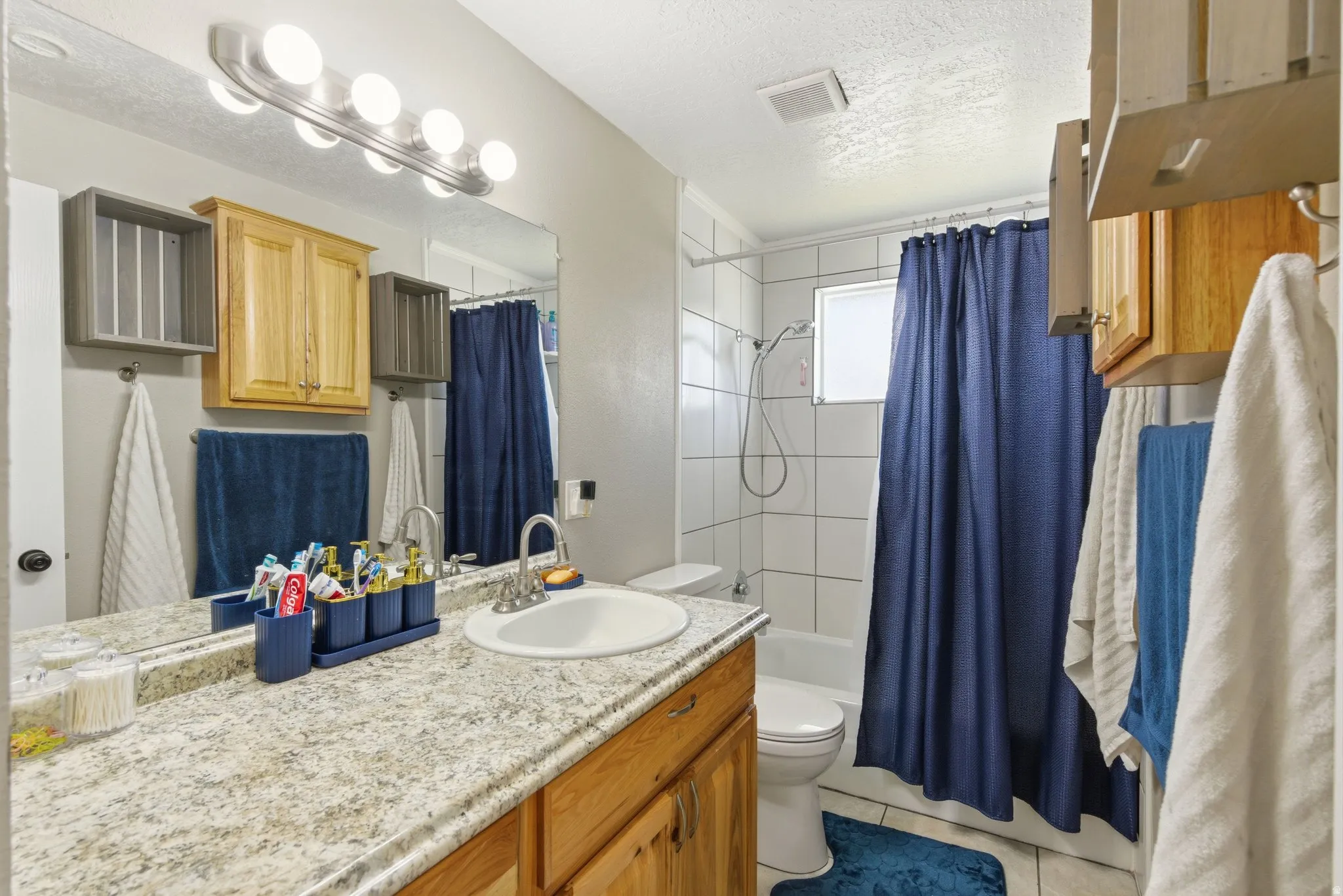 Bathroom featuring a wood-finish vanity with a granite-style countertop, undermount sink, and brushed nickel faucet