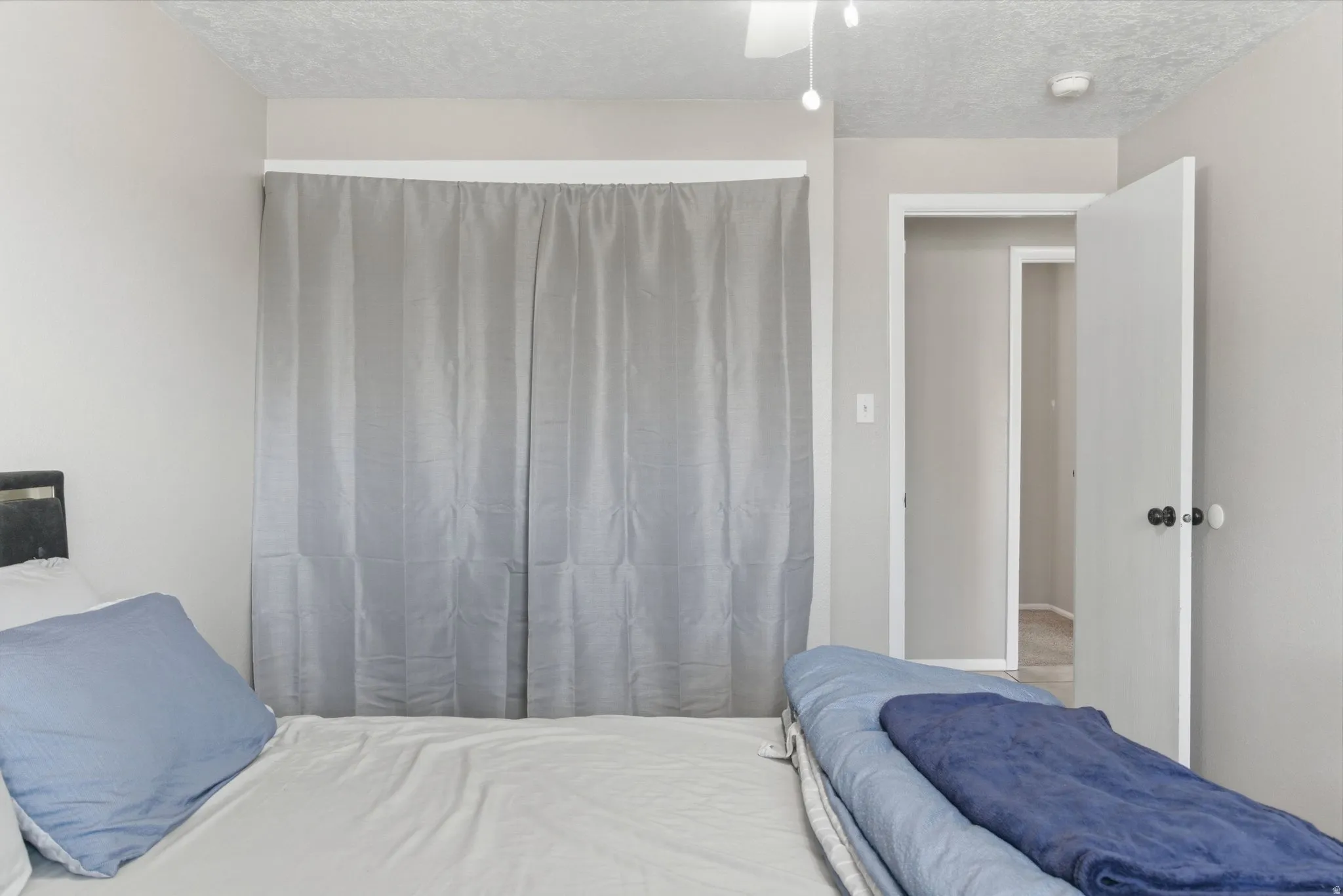 Bedroom featuring light gray walls, white trim, a ceiling fan with integrated lighting, and a closet with gray curtain doors