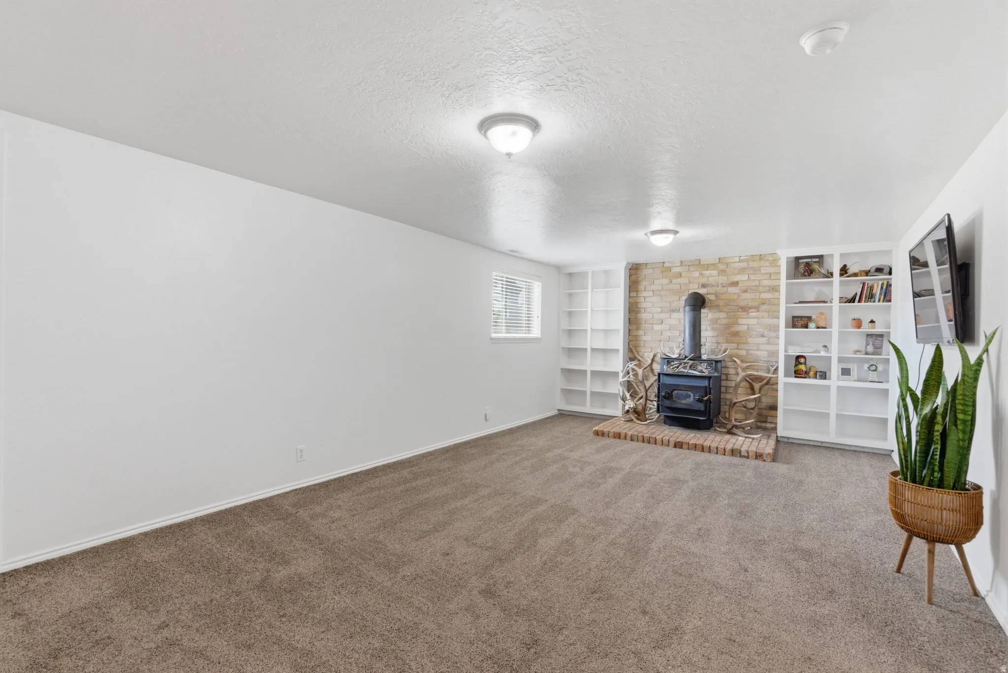 Living area with neutral carpeting, recessed lighting, and a brick-detailed fireplace