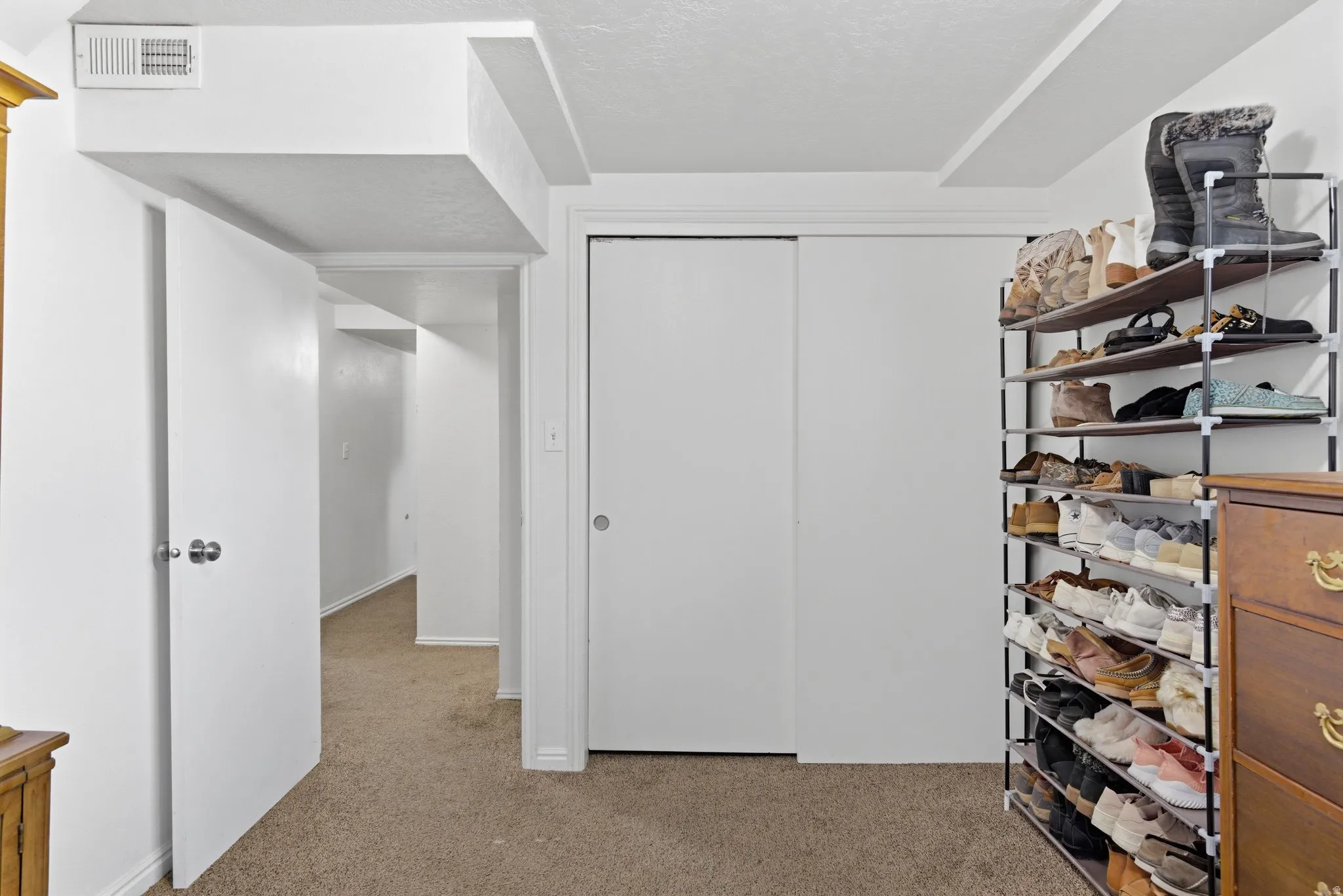 Carpeted interior area featuring white walls, white trim, and a white ceiling with visible ductwork