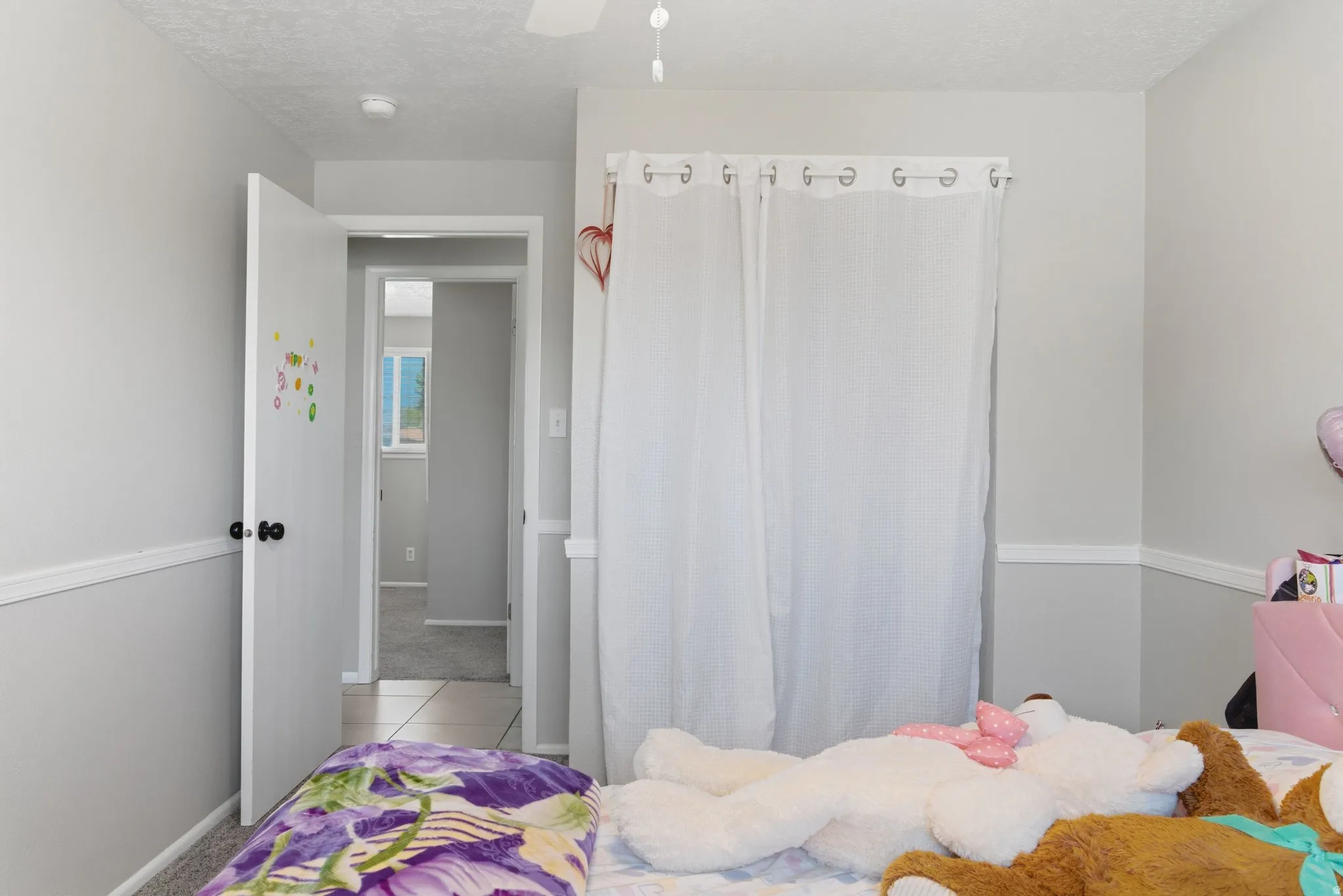 Light gray walls with white chair rail molding, white interior door with black hardware, and a white ceiling fan