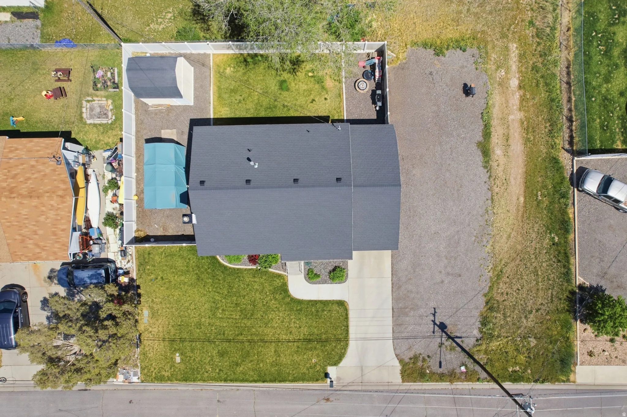 Main residence featuring a dark shingle roof, concrete driveway, and a fenced backyard