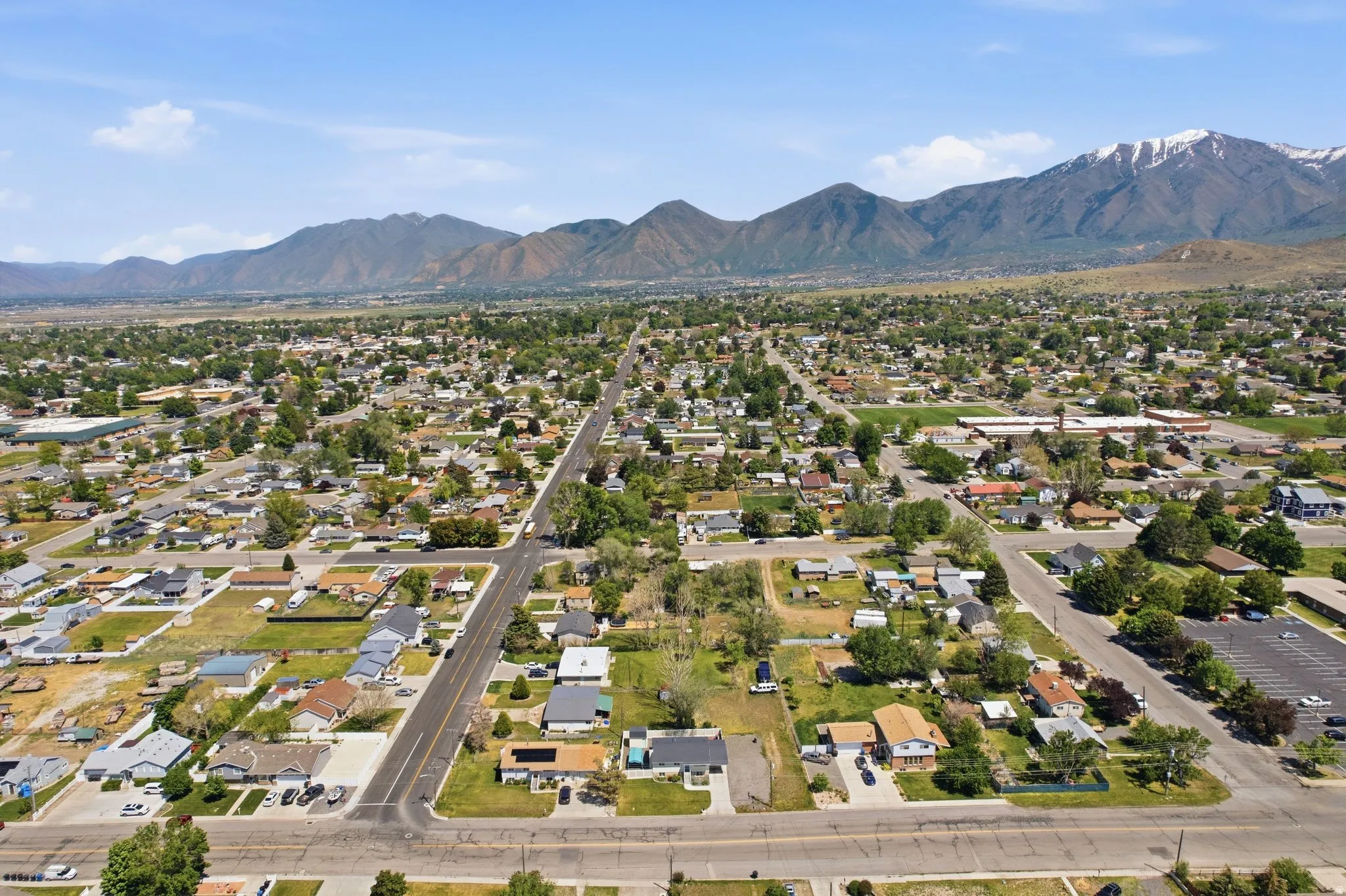 Expansive residential area with numerous single-story homes, mature trees, paved streets, and a prominent mountain range backdrop