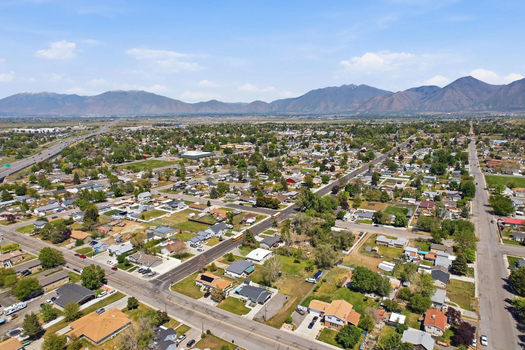 Expansive neighborhood perspective featuring a mountainous backdrop, mature trees, a network of residential streets, and individual properties with varied rooflines
