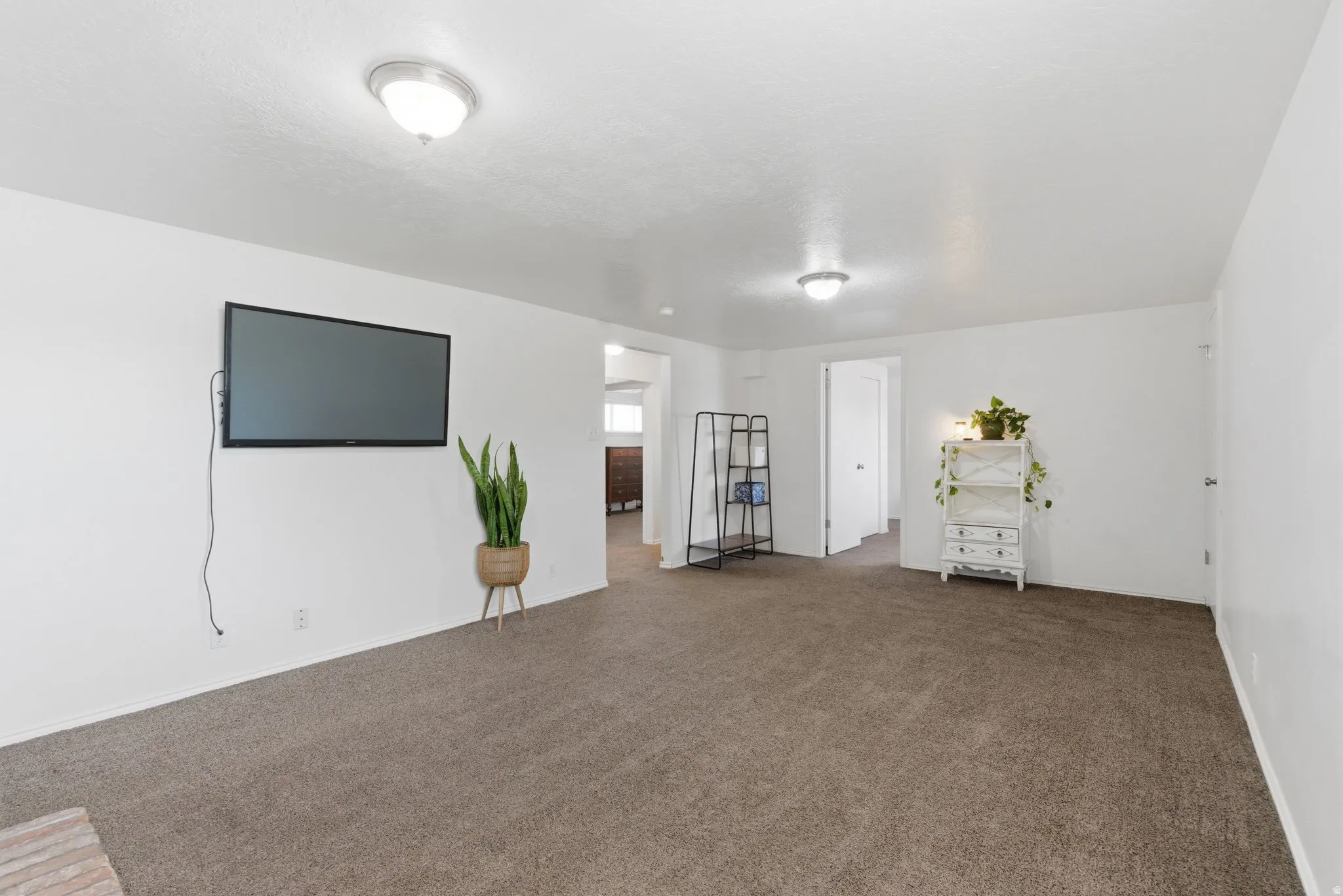 Carpeted living area featuring white walls and ceiling-mounted dome lights