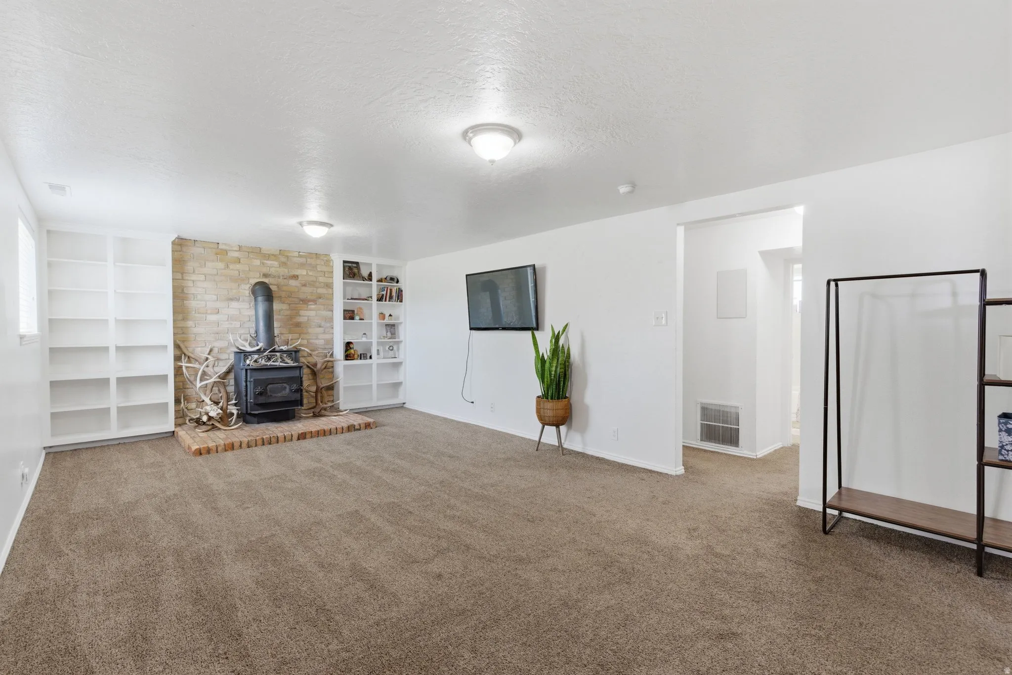 Spacious room featuring a brick-surround wood-burning stove with a brick hearth, flanked by built-in shelving units