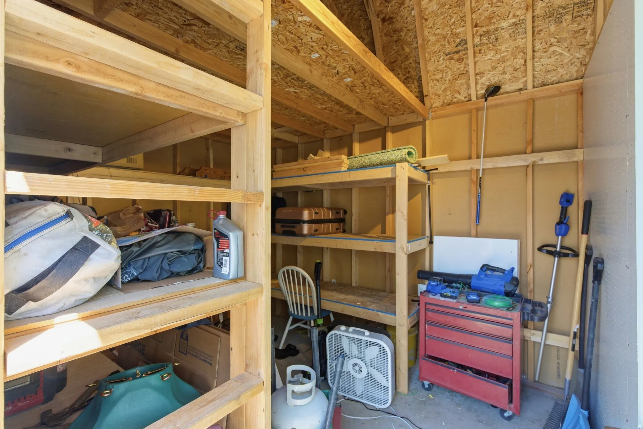 Interior shed with exposed wood framing, built-in shelving, and a pitched roofline