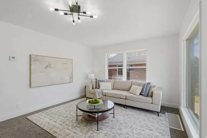 Living area featuring white walls, gray carpeting, and a modern ceiling light fixture