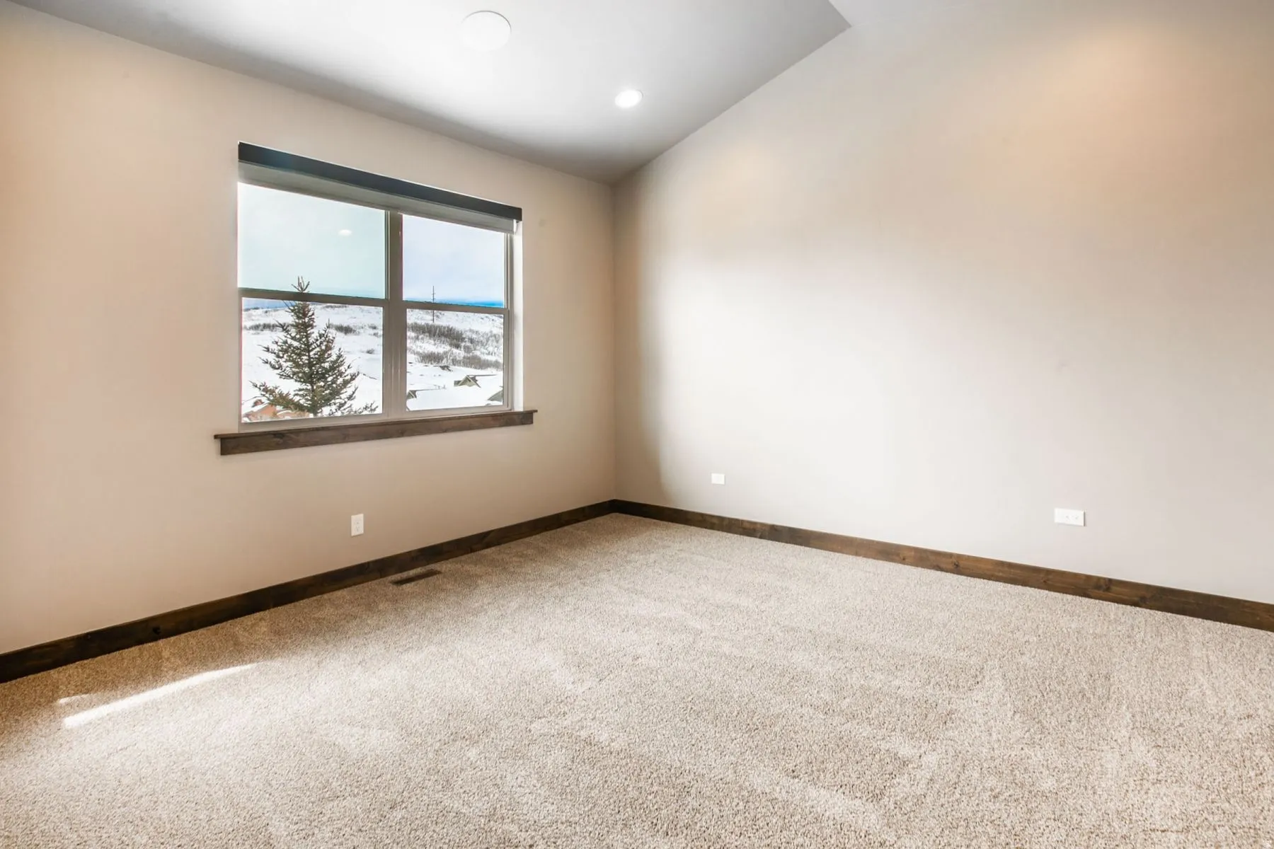 Carpeted room featuring a large window with a dark wood-finish sill, recessed lighting, and sloped ceilings