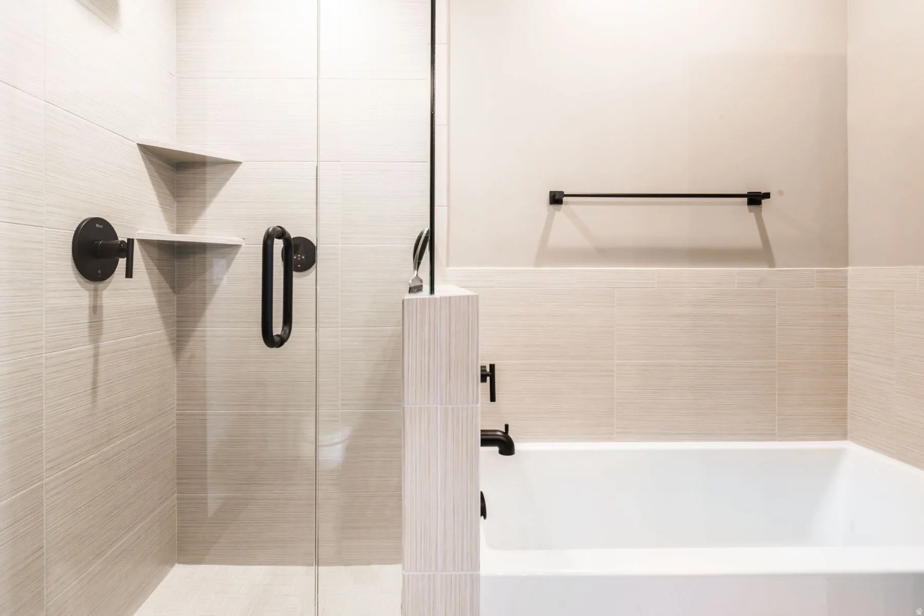 Contemporary bathroom featuring a clear glass shower enclosure, integrated shower shelving, a white soaking tub, and matte black fixtures