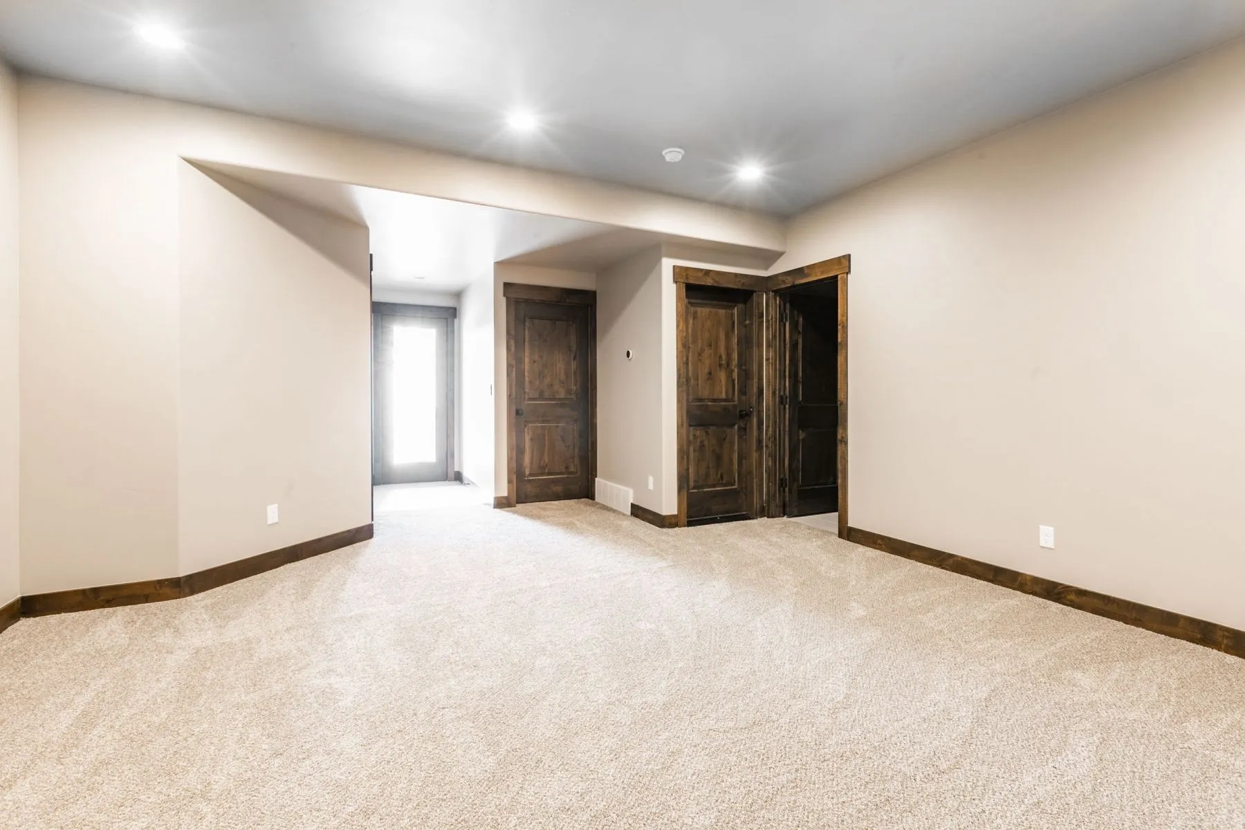Spacious interior room featuring light-colored wall paint, recessed lighting, and light-toned carpet