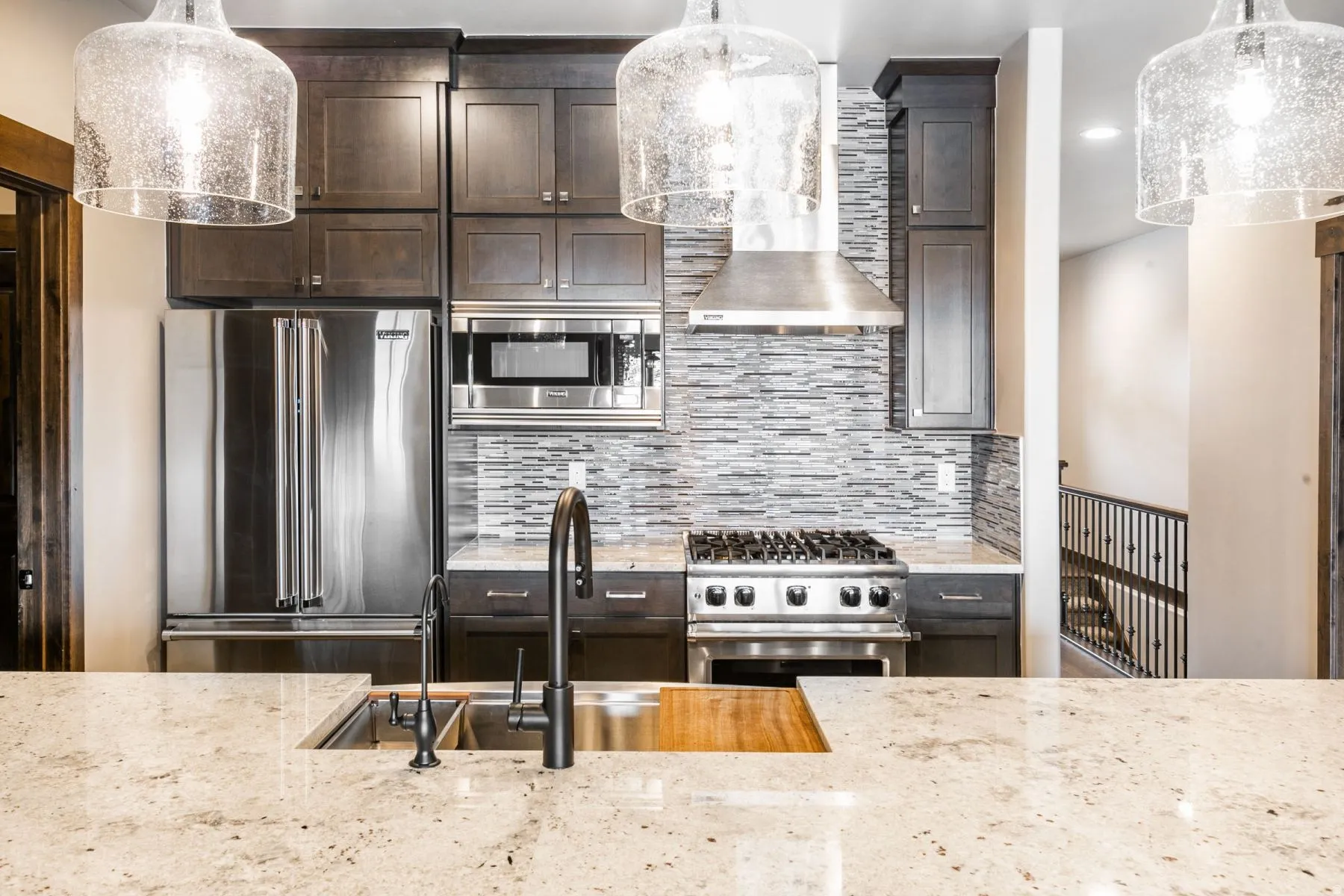 Modern kitchen featuring a large kitchen island with a double basin stainless steel sink and matte black gooseneck faucet