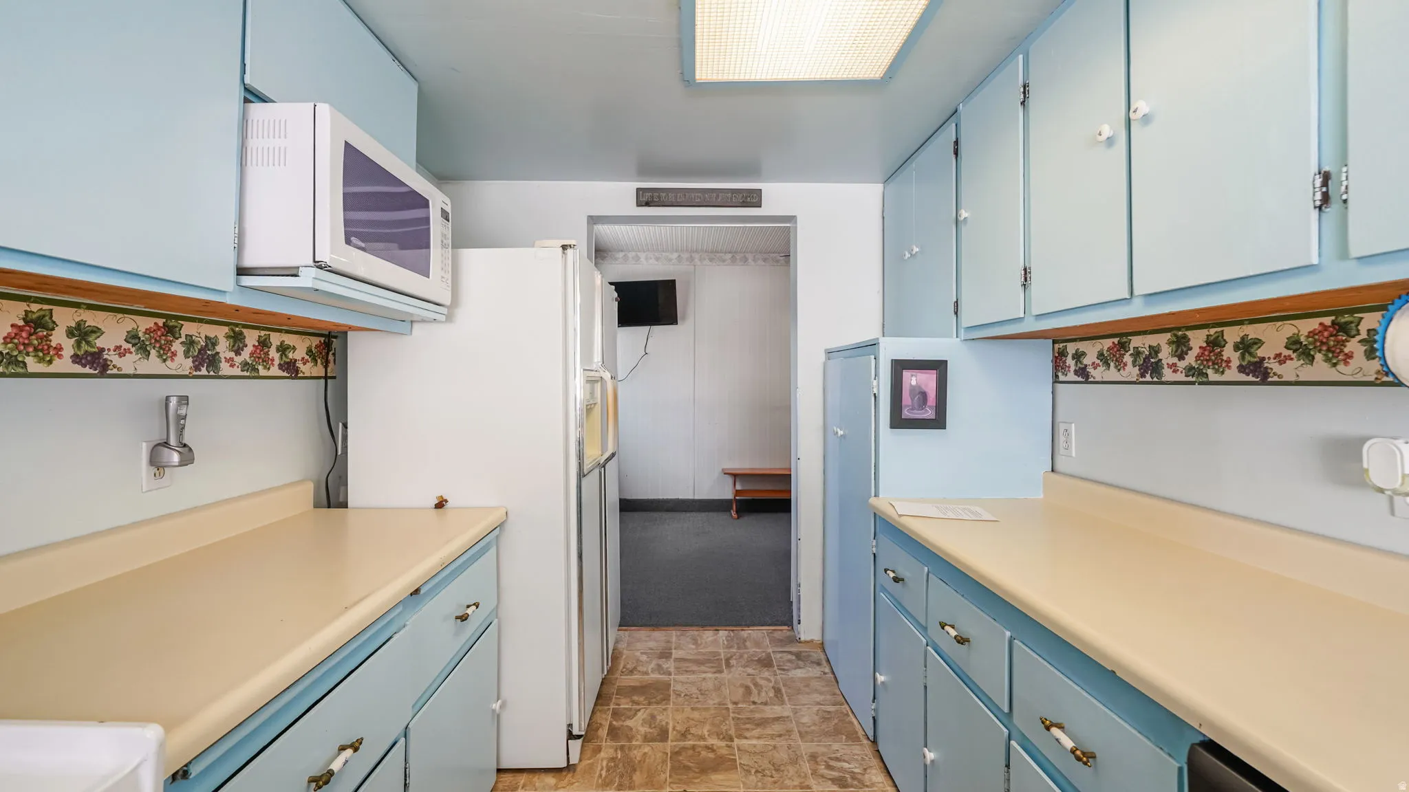Galley-style kitchen featuring light blue cabinetry, light-colored countertops, and wood-finish flooring