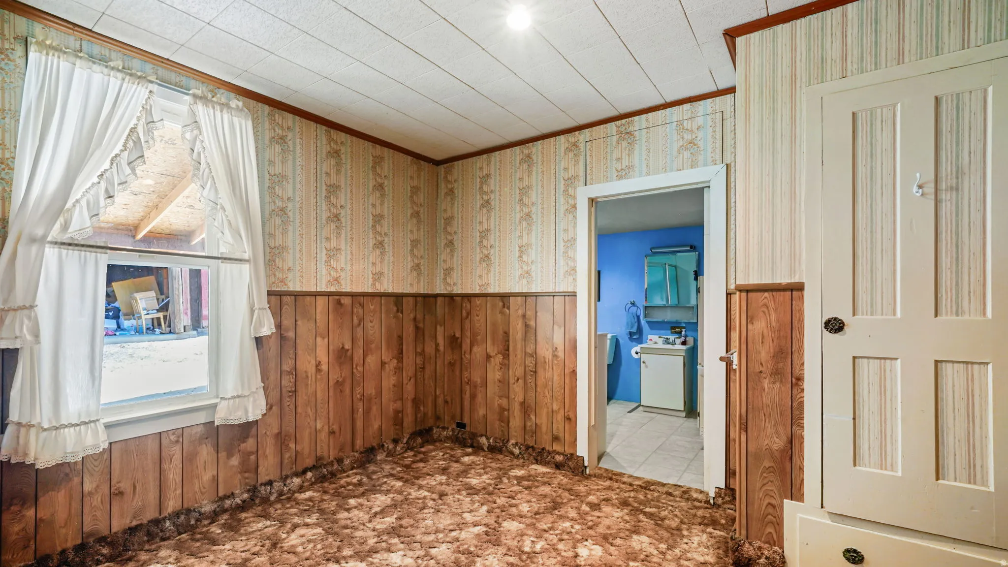 Room featuring wood-finish paneling, patterned wallpaper, and textured ceiling panels
