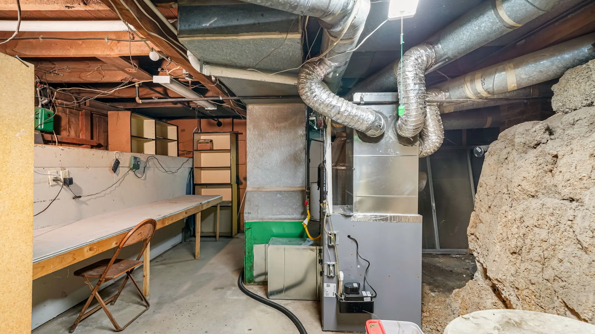 Basement utility space featuring exposed ceiling joists, various ductwork, and a furnace unit