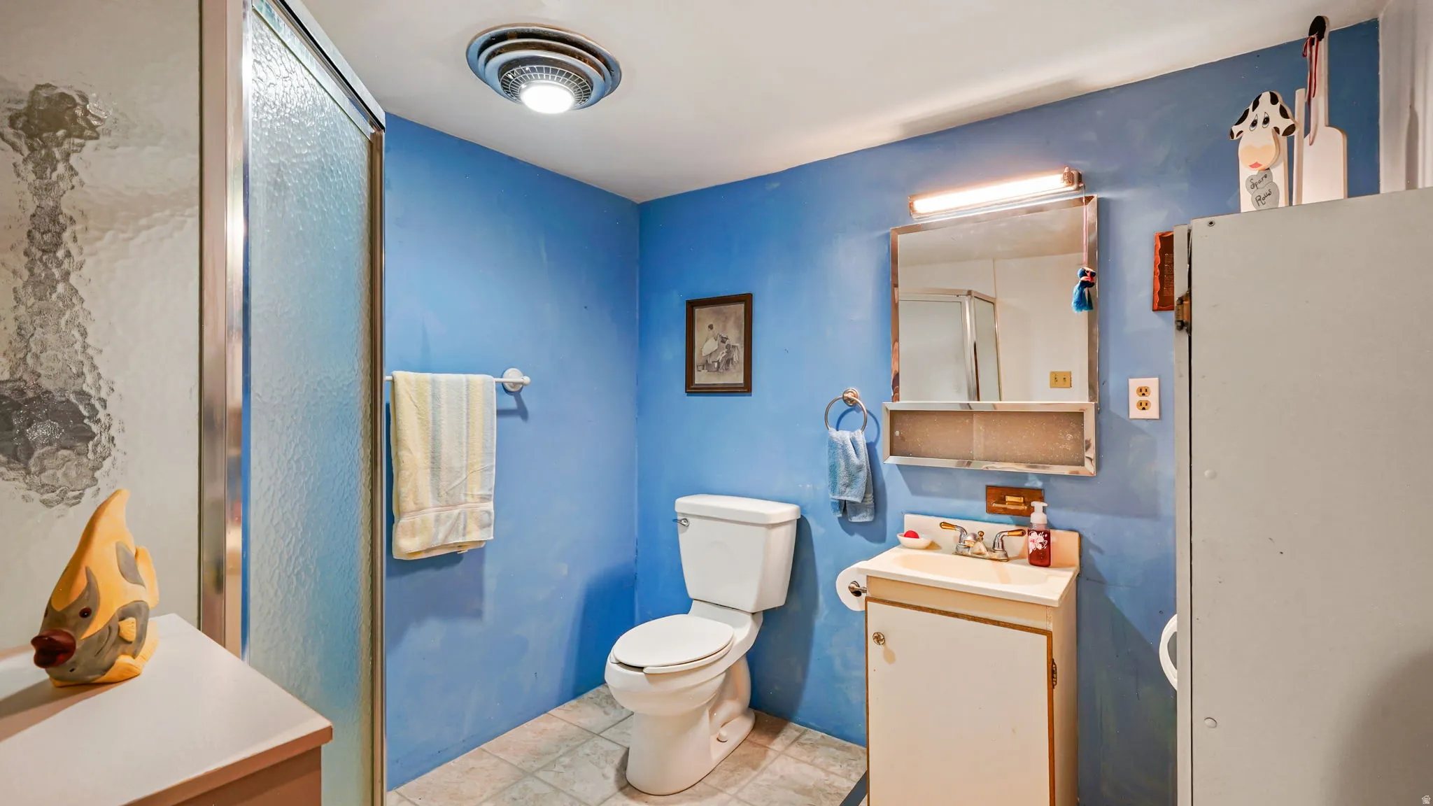 Bathroom featuring a glass-enclosed shower, a white toilet, and a vanity with a sink and storage