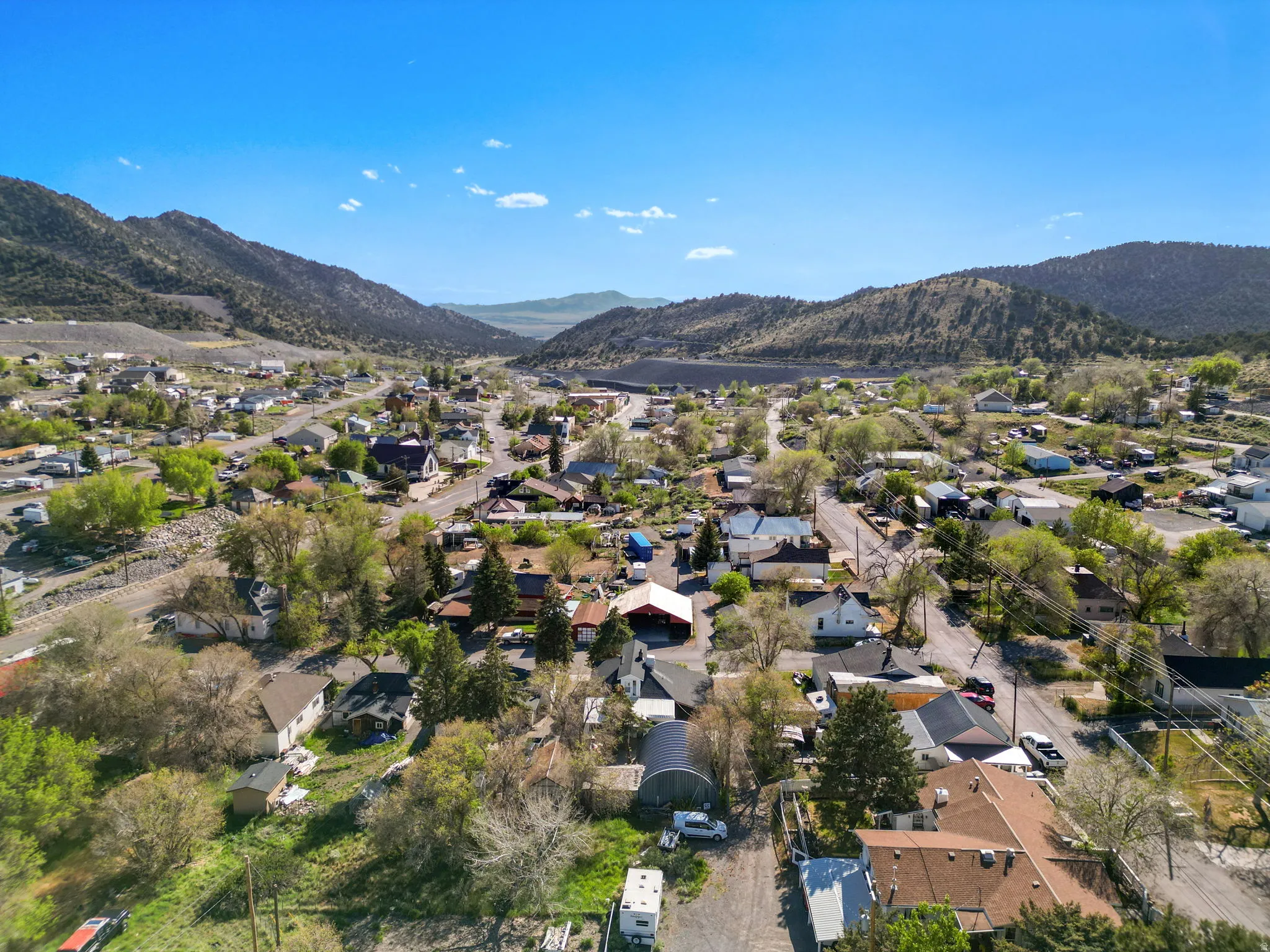 Expansive aerial perspective showcasing a residential area nestled within a mountainous landscape under a clear sky