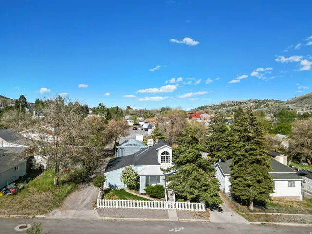Aerial perspective showcasing a light blue residence with a dark roof and a white picket fence