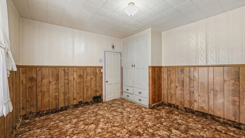 Room featuring wall paneling, a built-in wardrobe with four drawers, and a ceiling-mounted light fixture