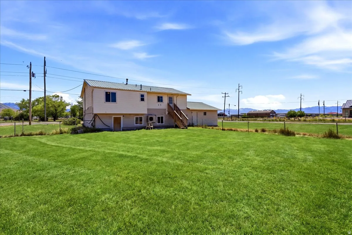 Expansive green lawn with a white exterior structure featuring a green metal roof and a wooden exterior staircase