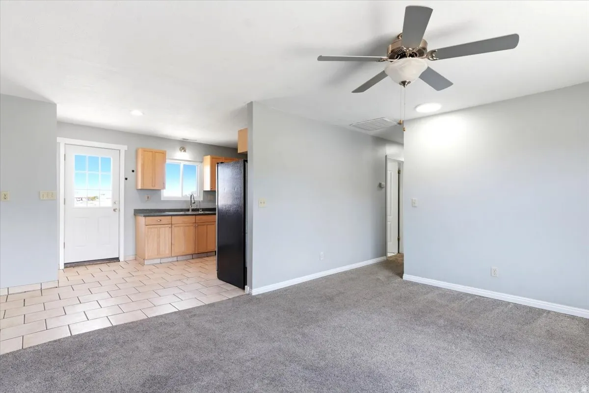 Open concept living space featuring a carpeted area and a kitchen with tile flooring