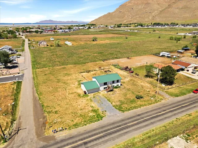 Expansive property featuring a residence with a green roof, surrounding agricultural fields, and a distant body of water with mountains